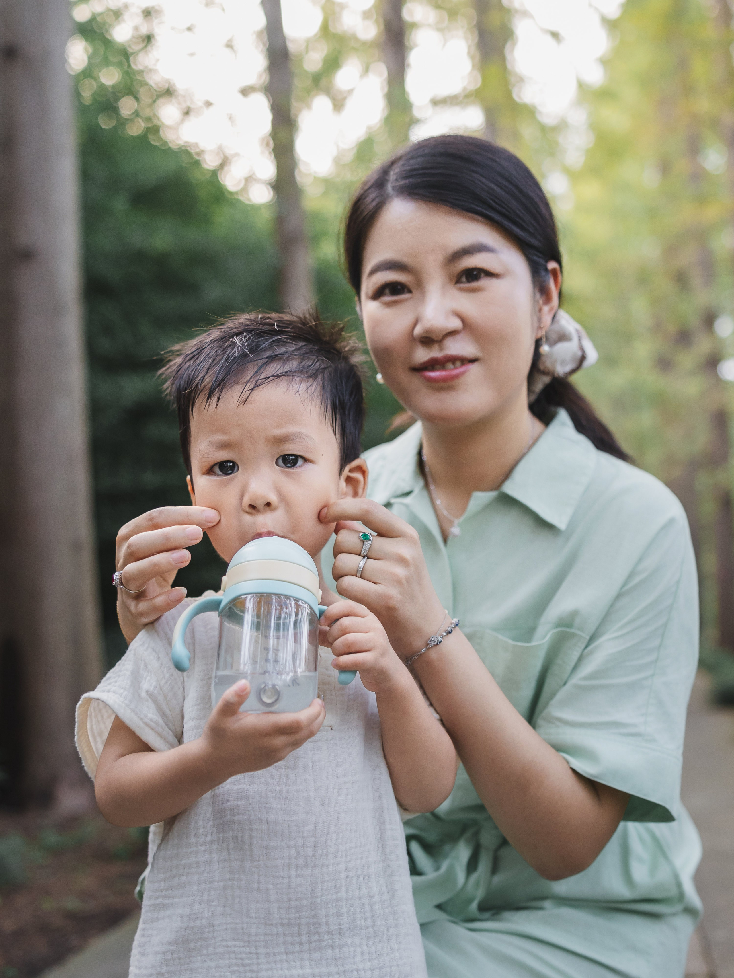 Mom helps her child drink from a bottle in a close, caring Shanghai family photography moment.