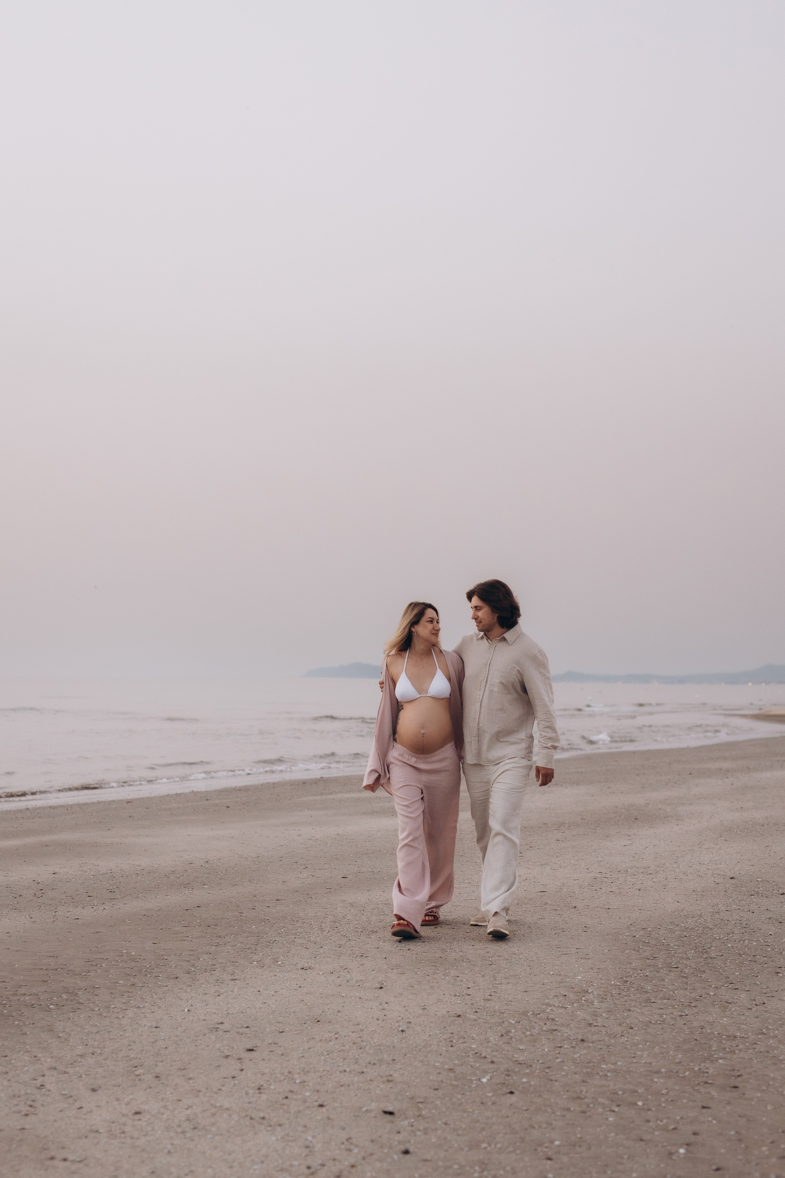 Coppia in gravidanza che cammina sulla spiaggia a Rimini — servizio fotografico maternity
