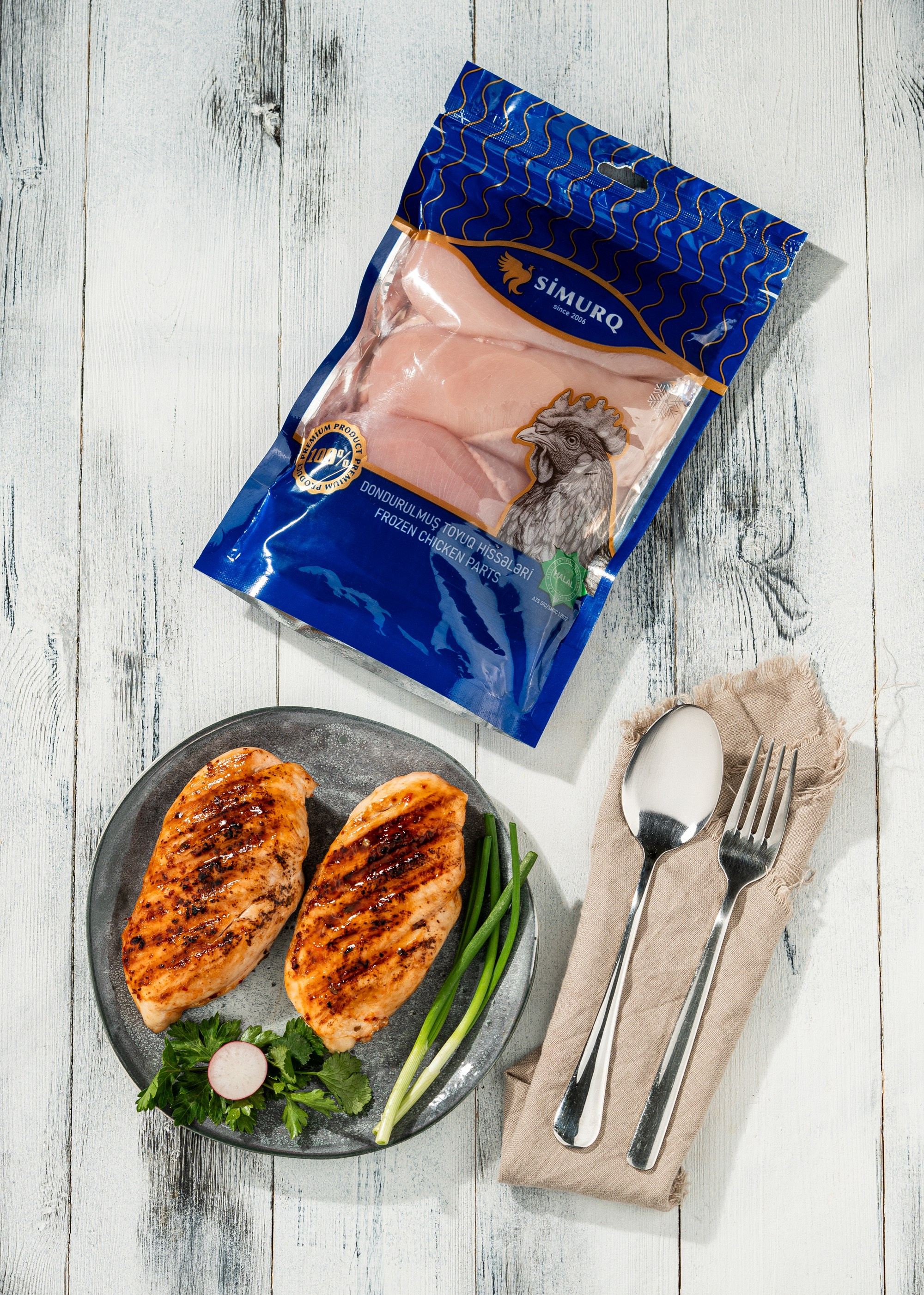 Bişmiş toyuq filesi və Simurq qablaşdırmasında dondurulmuş toyuq filesi – ağ fonda qida stilistikası və məhsul təqdimatı