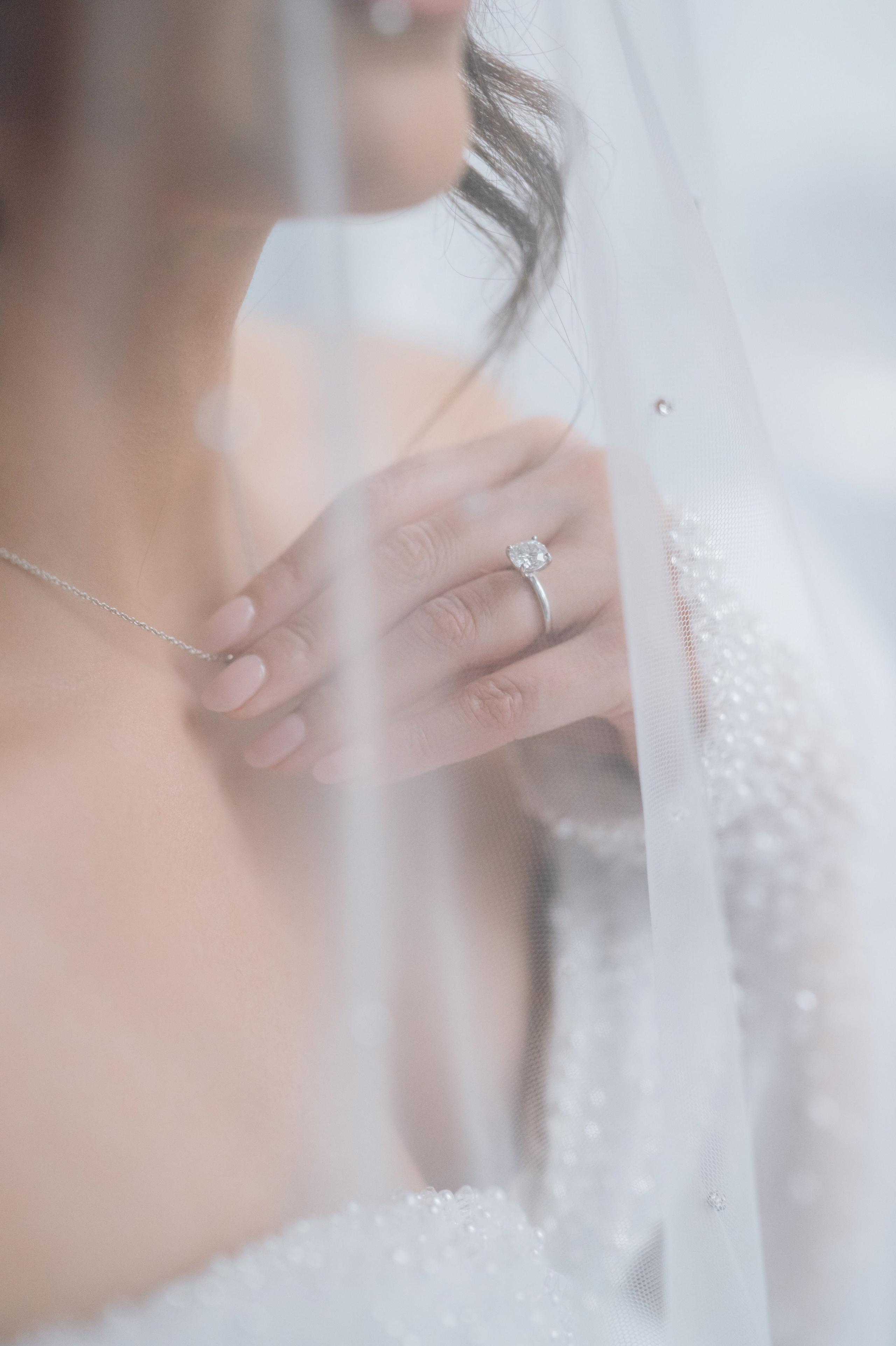 a bride's hand is seen through the veil of her wedding dress