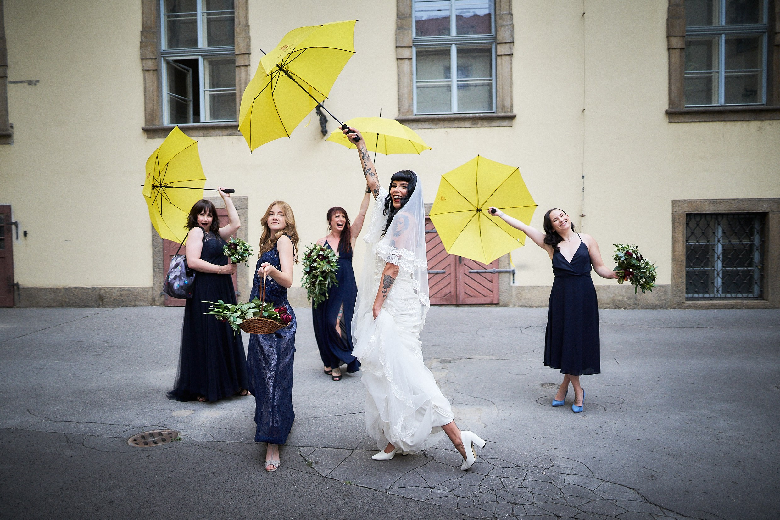 Bride and bridesmaids posing with colorful umbrellas in Prague rain.