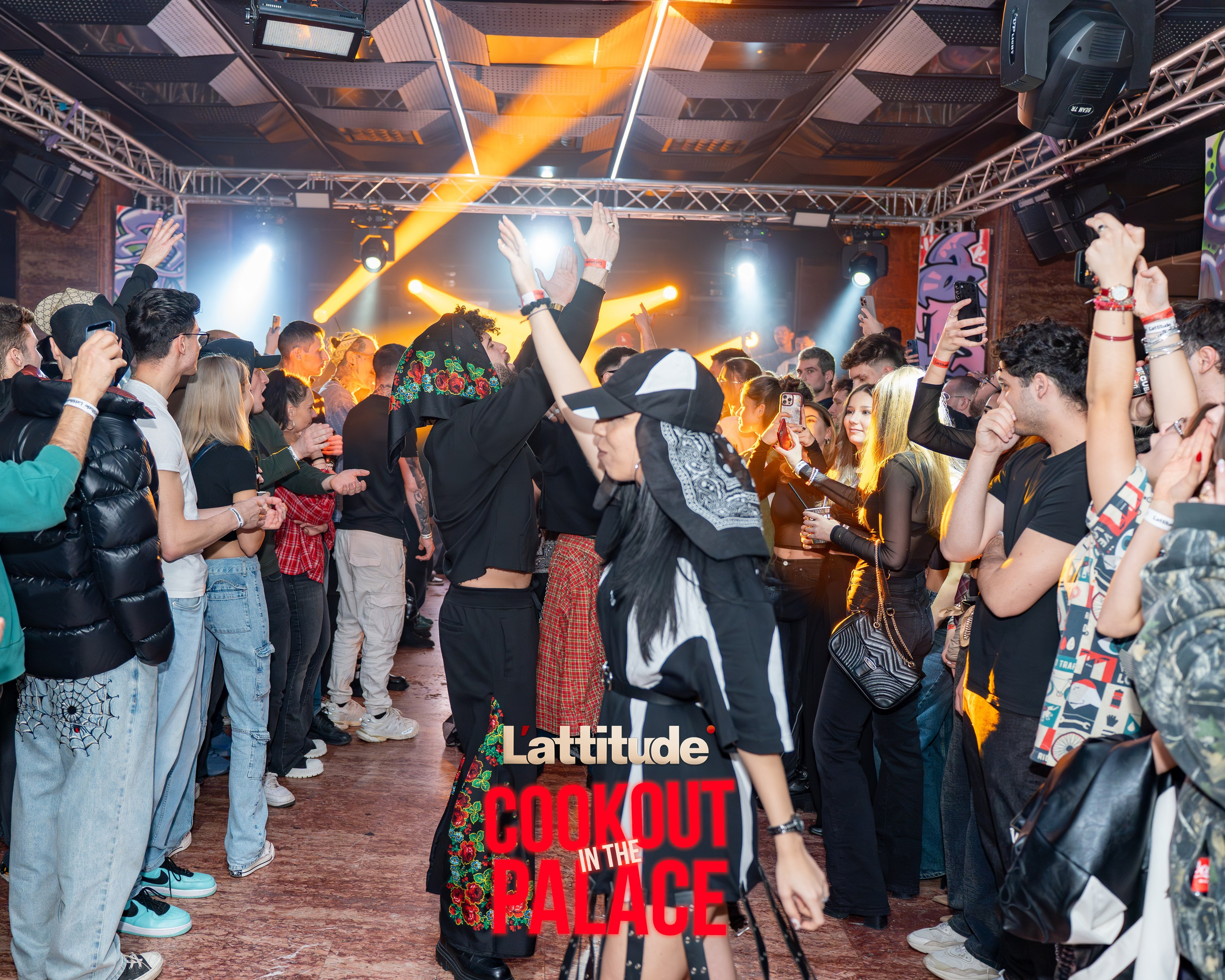 Crowd enjoying a lively indoor music event with colorful lights and energetic atmosphere.