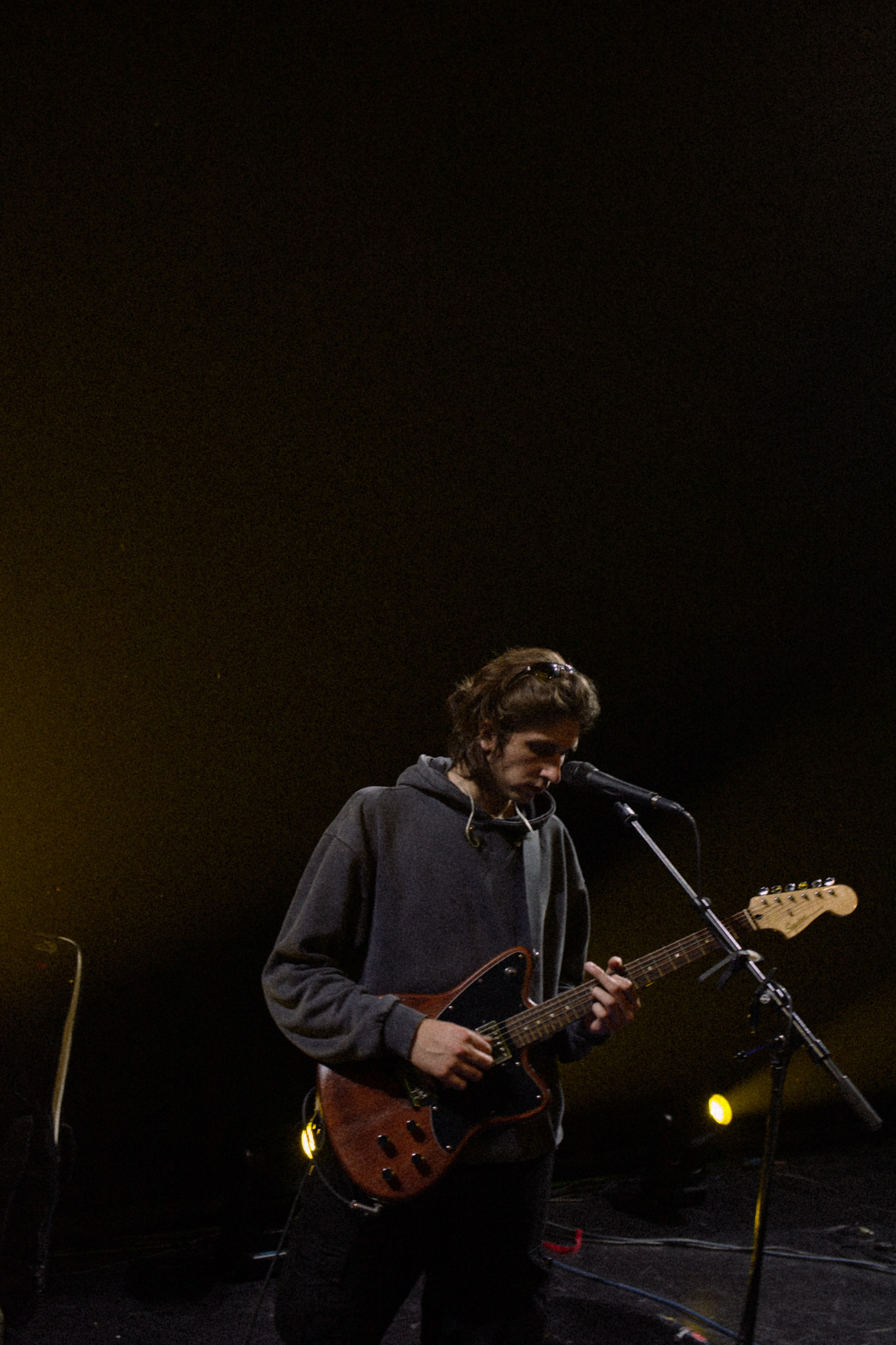 Guitarrista actuando en un escenario con poca luz