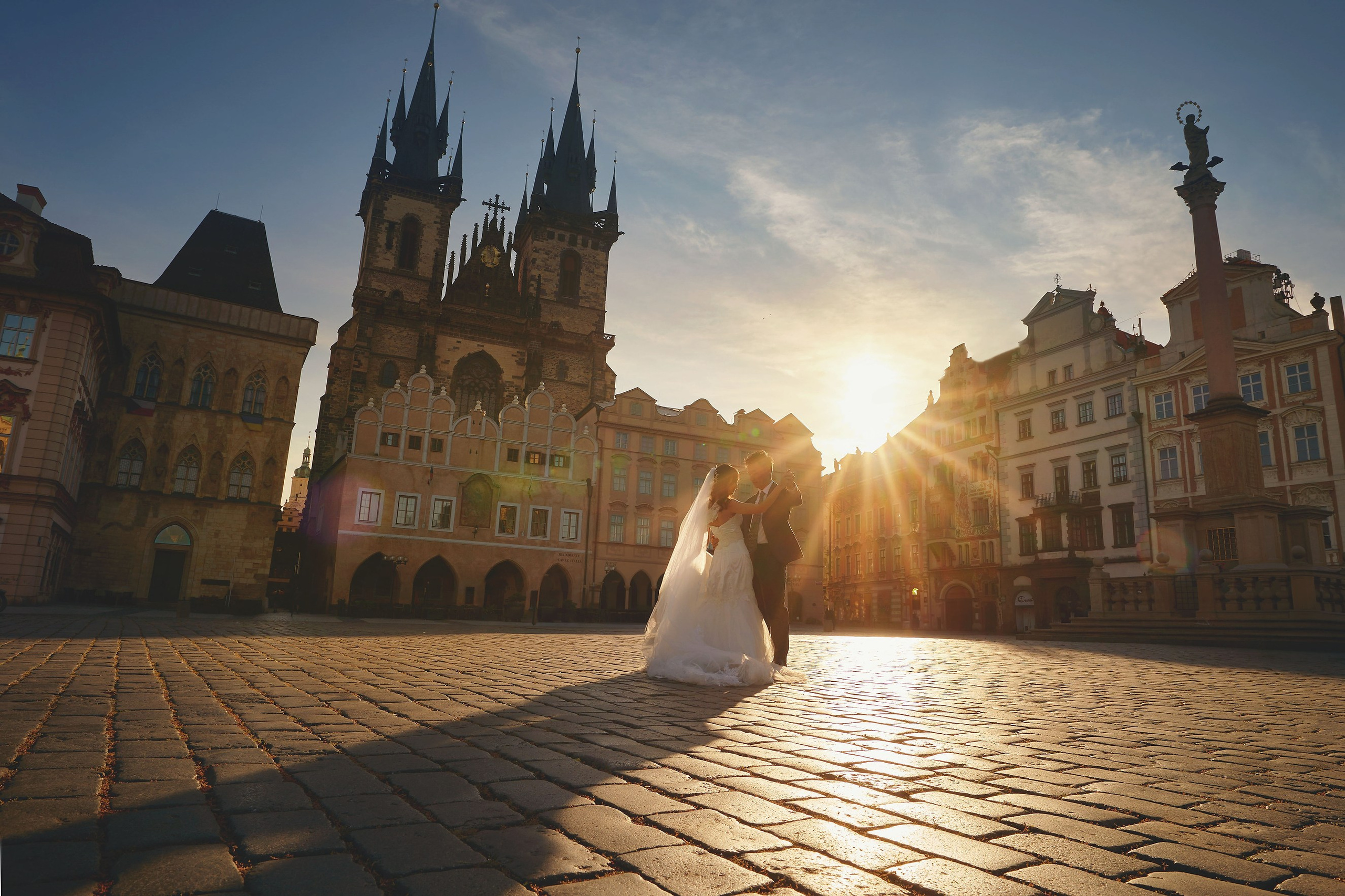 Eva and Conan waltzing hand in hand in sunlit Old Town Square, Prague.