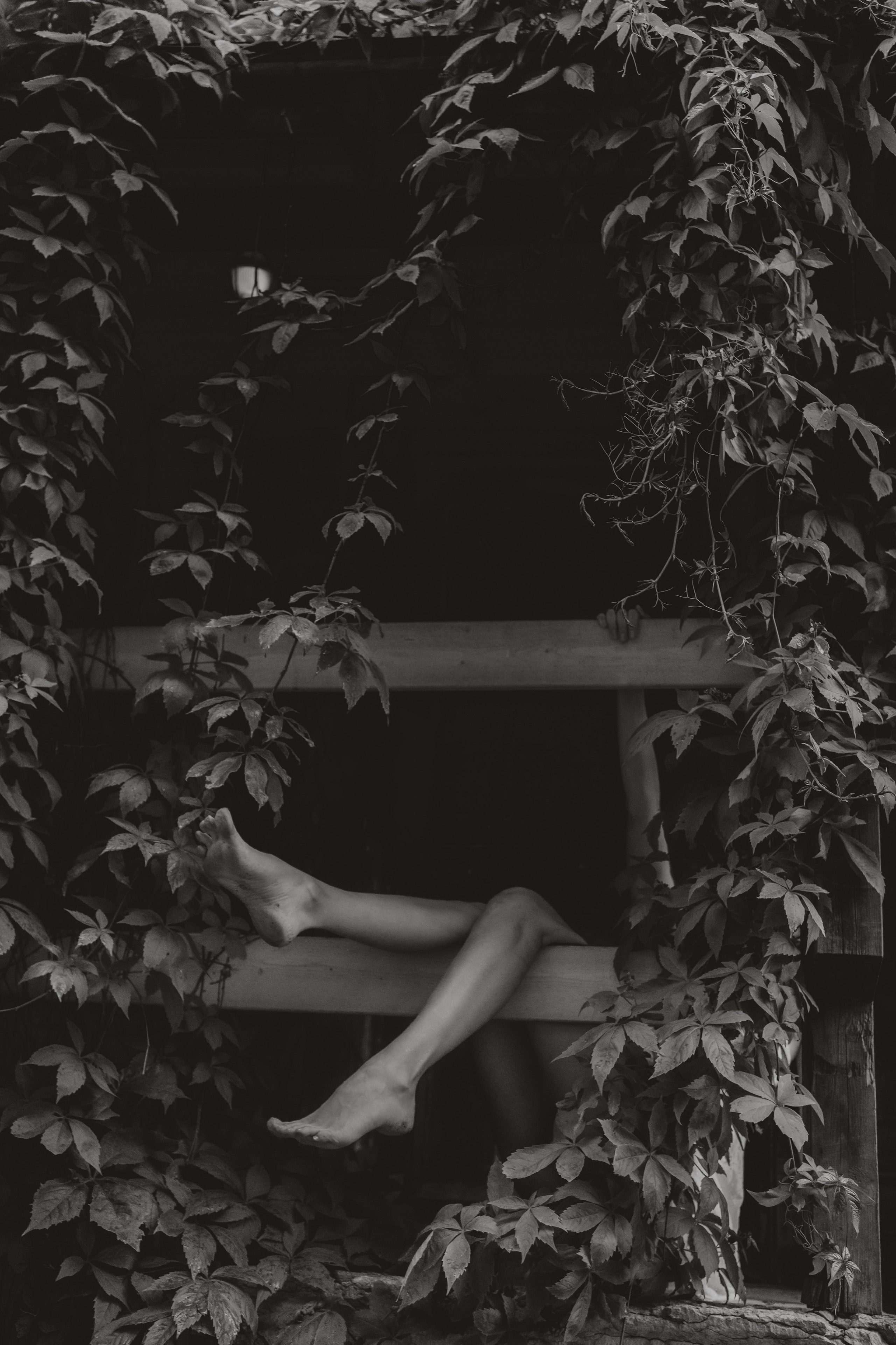 Fine art portrait of bare legs framed by ivy-covered architecture