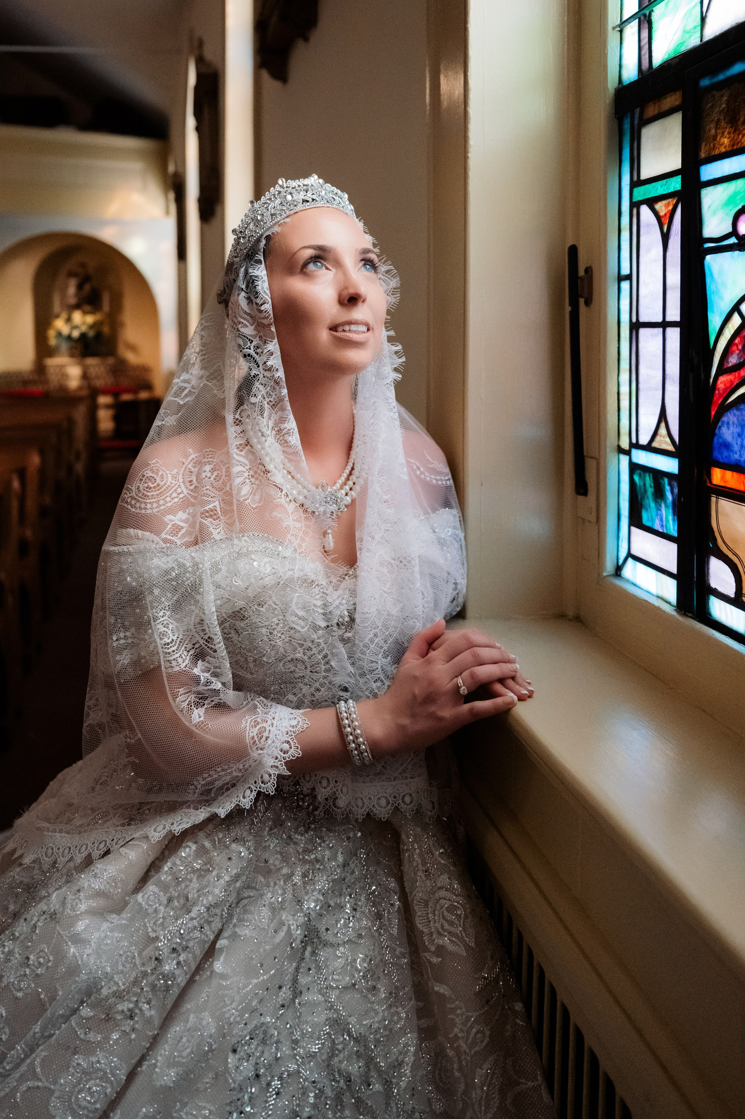 a woman in a wedding dress sitting by a window