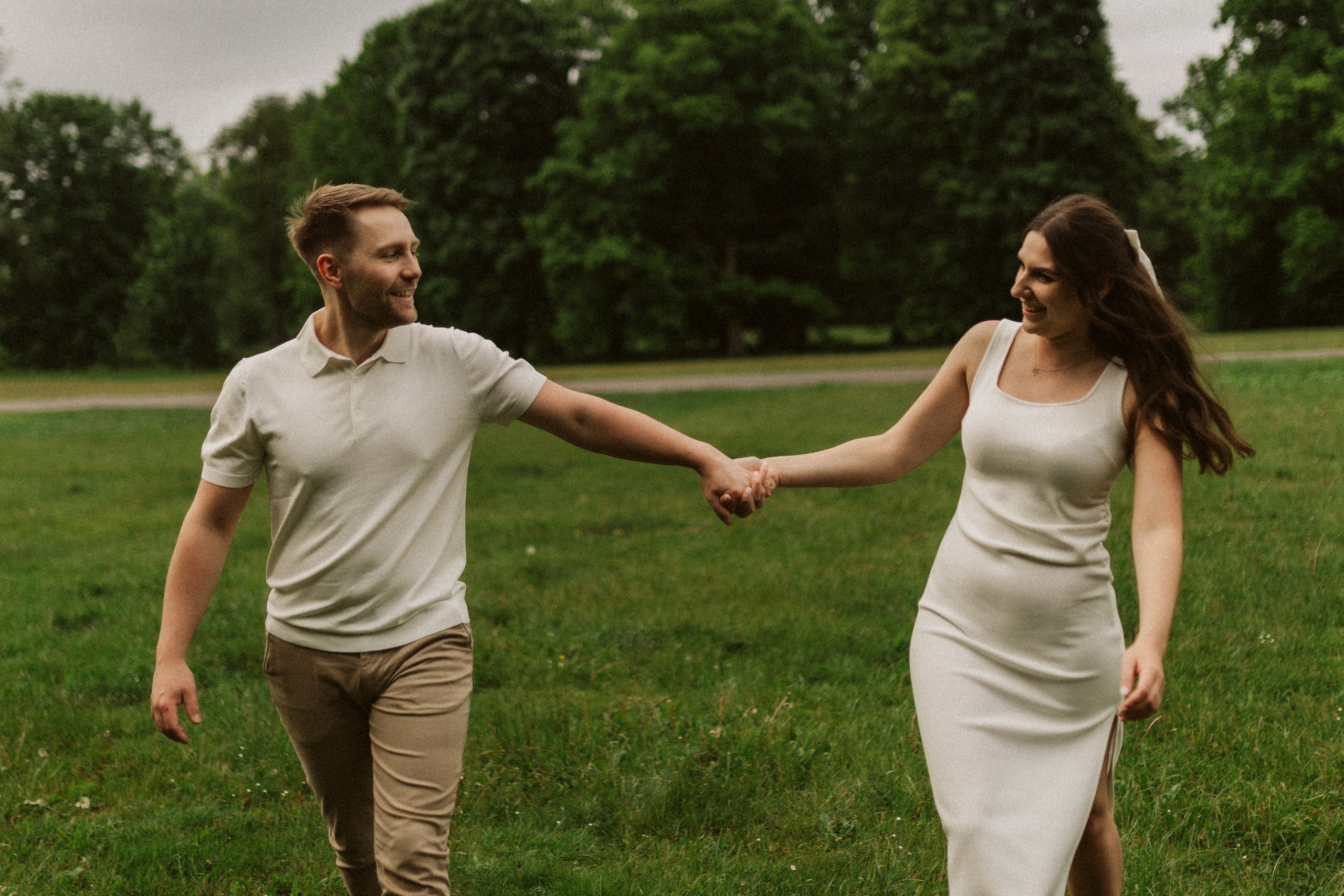 Sesja narzeczeńska w parku Świerklaniec – para idąca przez łąkę