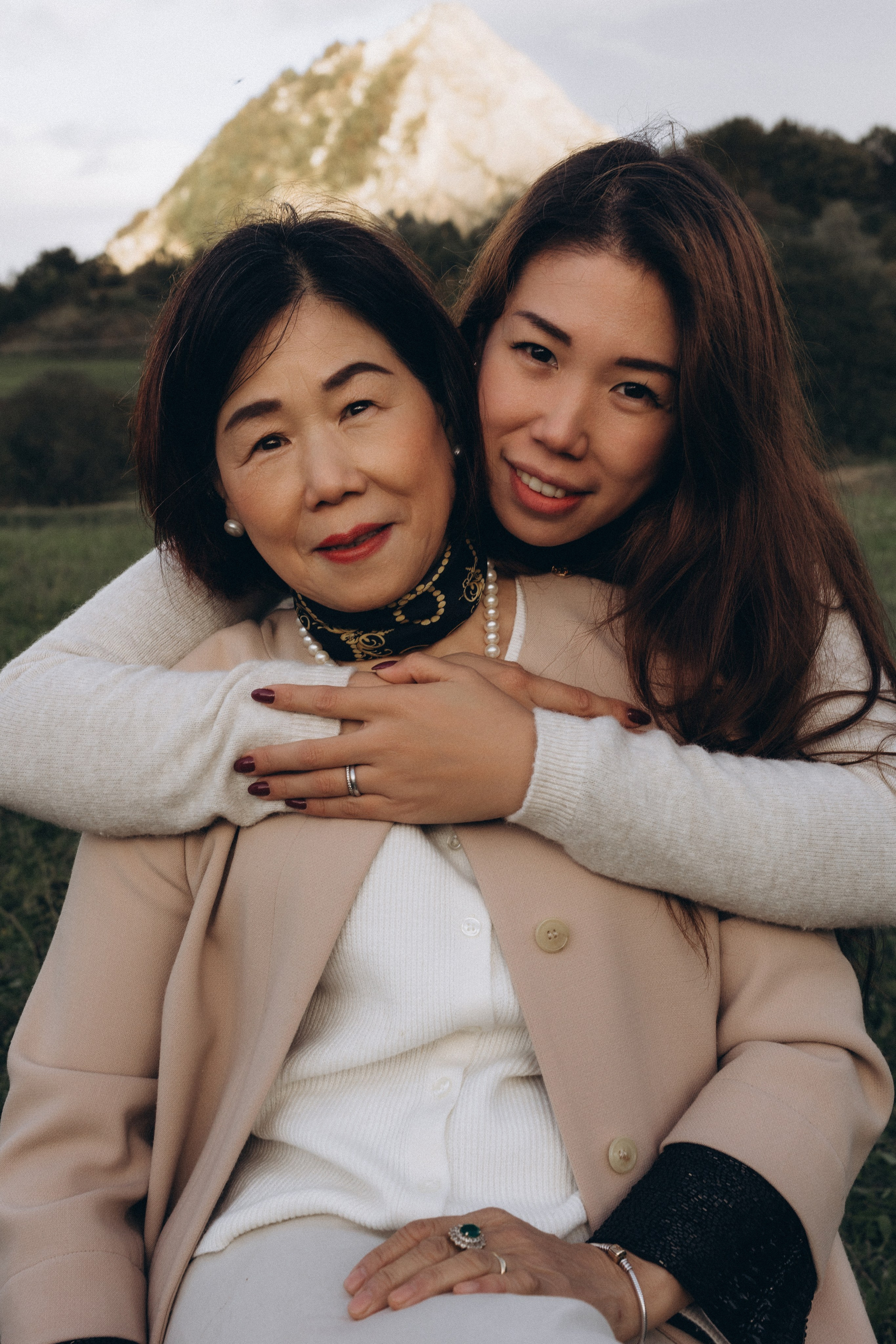 Ritratto di madre e figlia adulta abbracciate all’aperto sulle colline di San Marino, luce naturale e legame familiare autentico