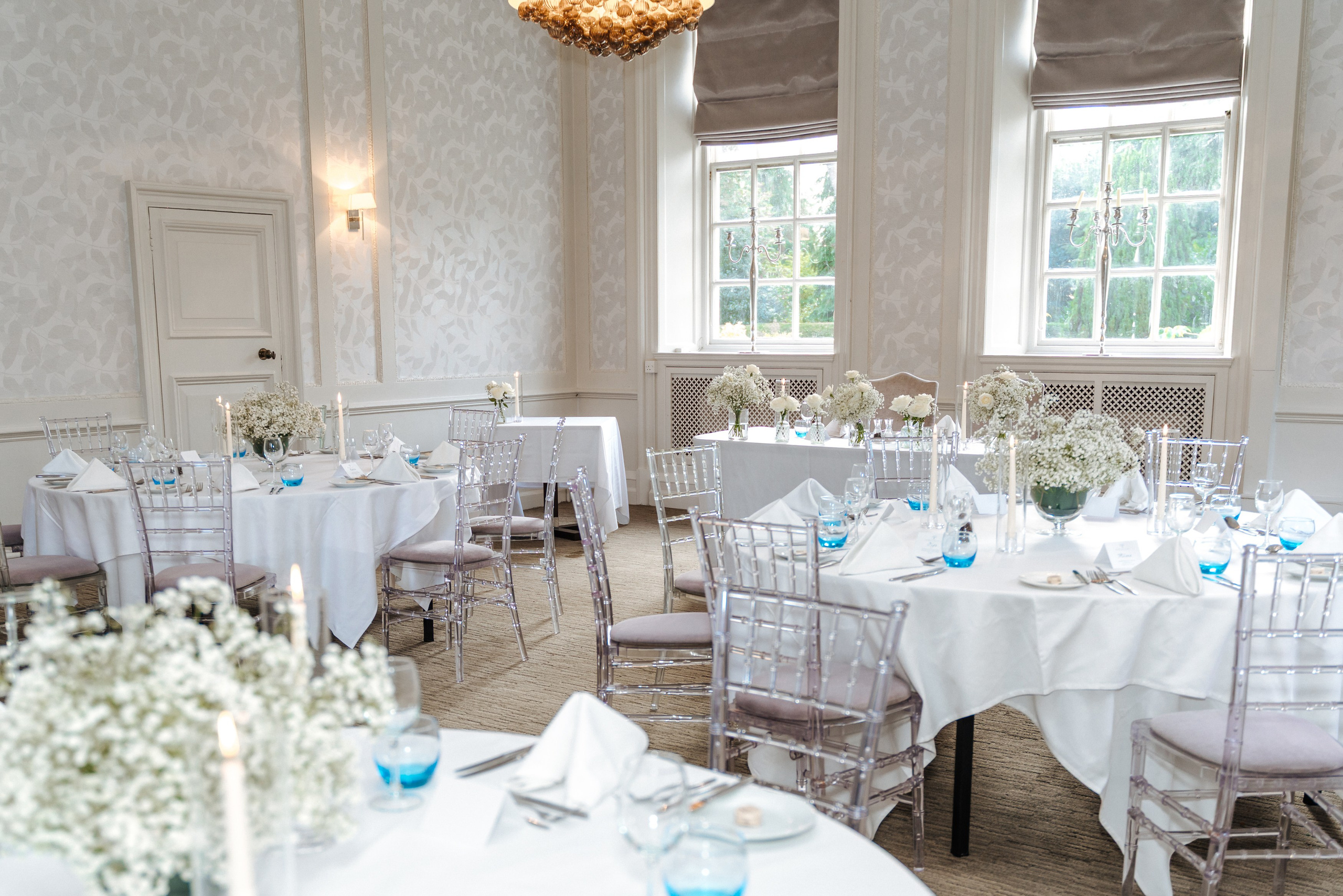 Elegant wedding reception setup at Barnet Hill Hotel, with white table linens, floral arrangements and blue glassware.