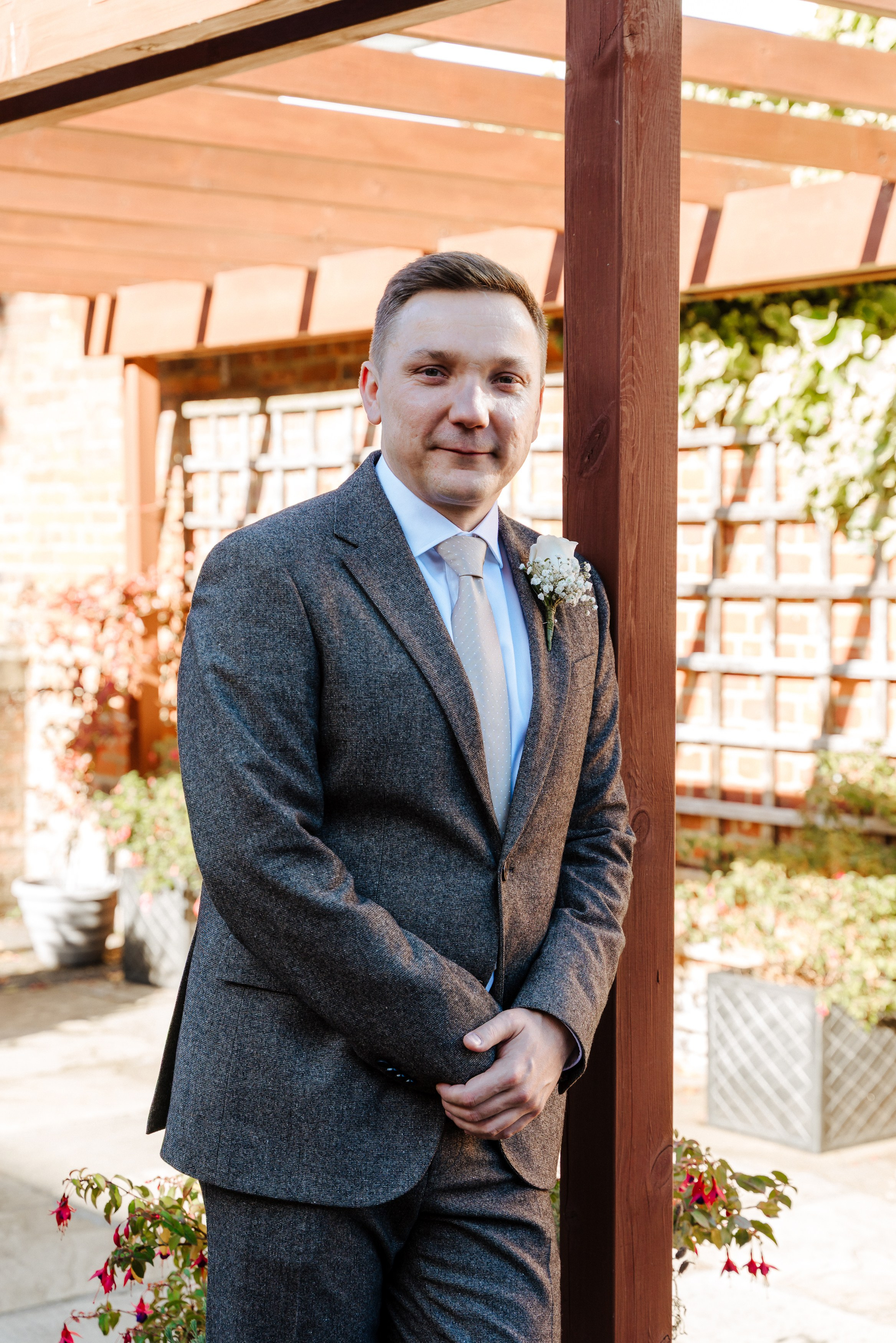 Groom Andrey in a tailored grey wedding suit and light blue tie, photographed outdoors at his Beaconsfield wedding.