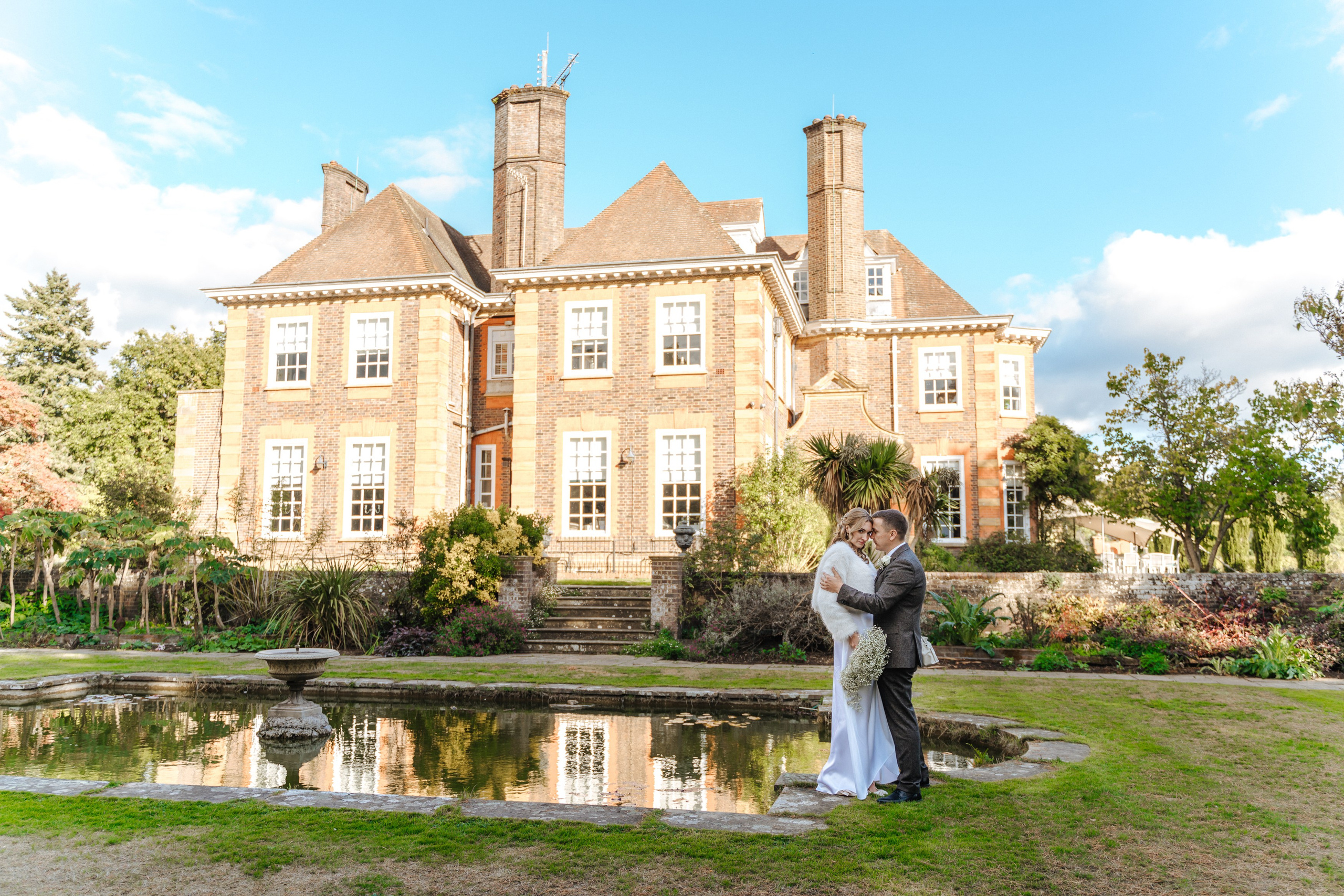 Andrey and Elena share a romantic embrace beneath a leafy garden arch during their wedding portrait session.