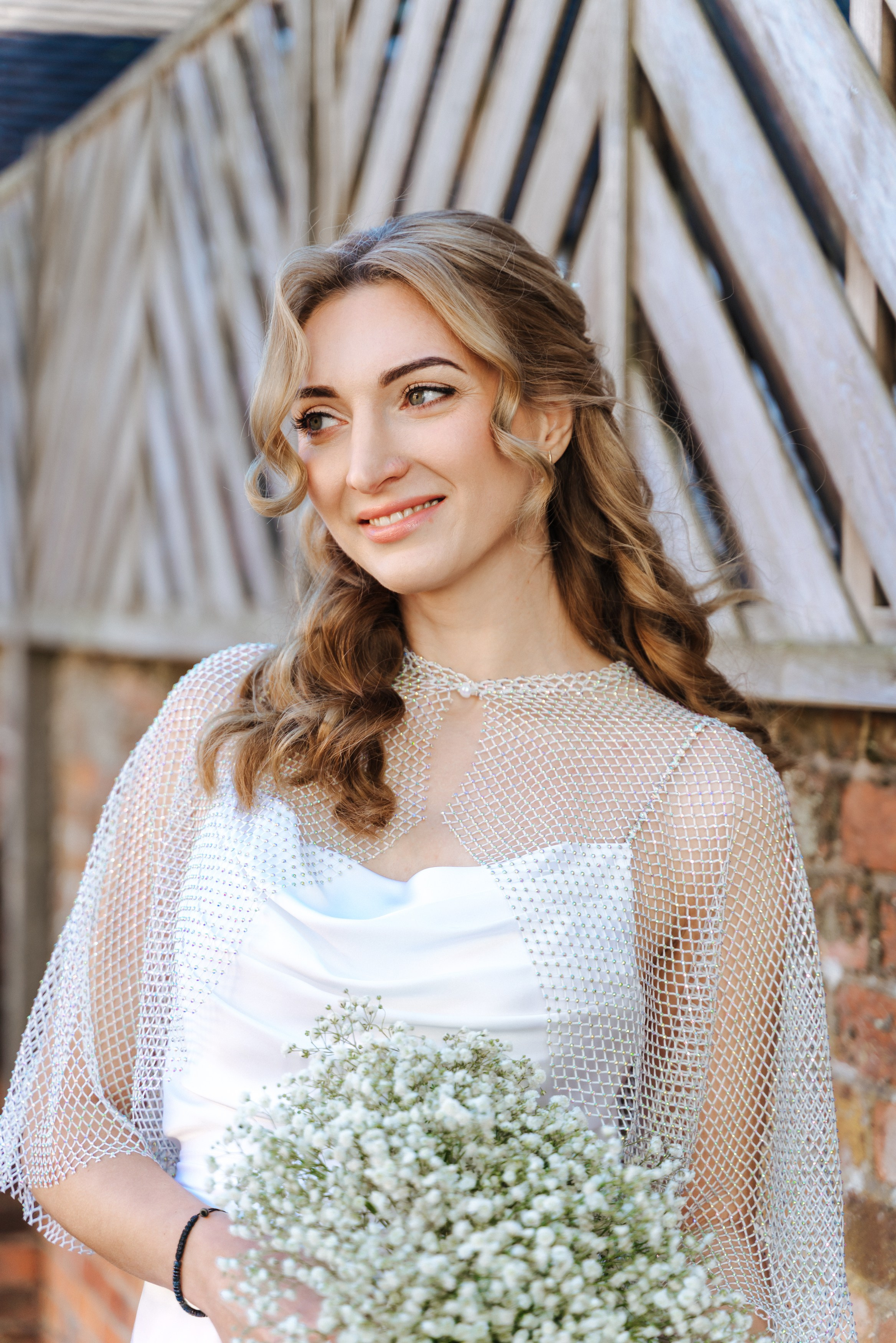 Bride Elena in an elegant white satin wedding dress holding a delicate gypsophila bouquet, photographed in natural light.
