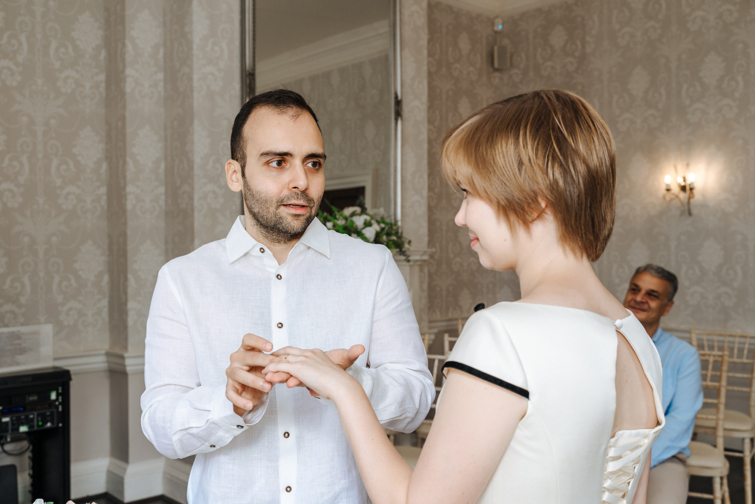 The groom slips the wedding ring onto his bride’s finger at Merton Register Office