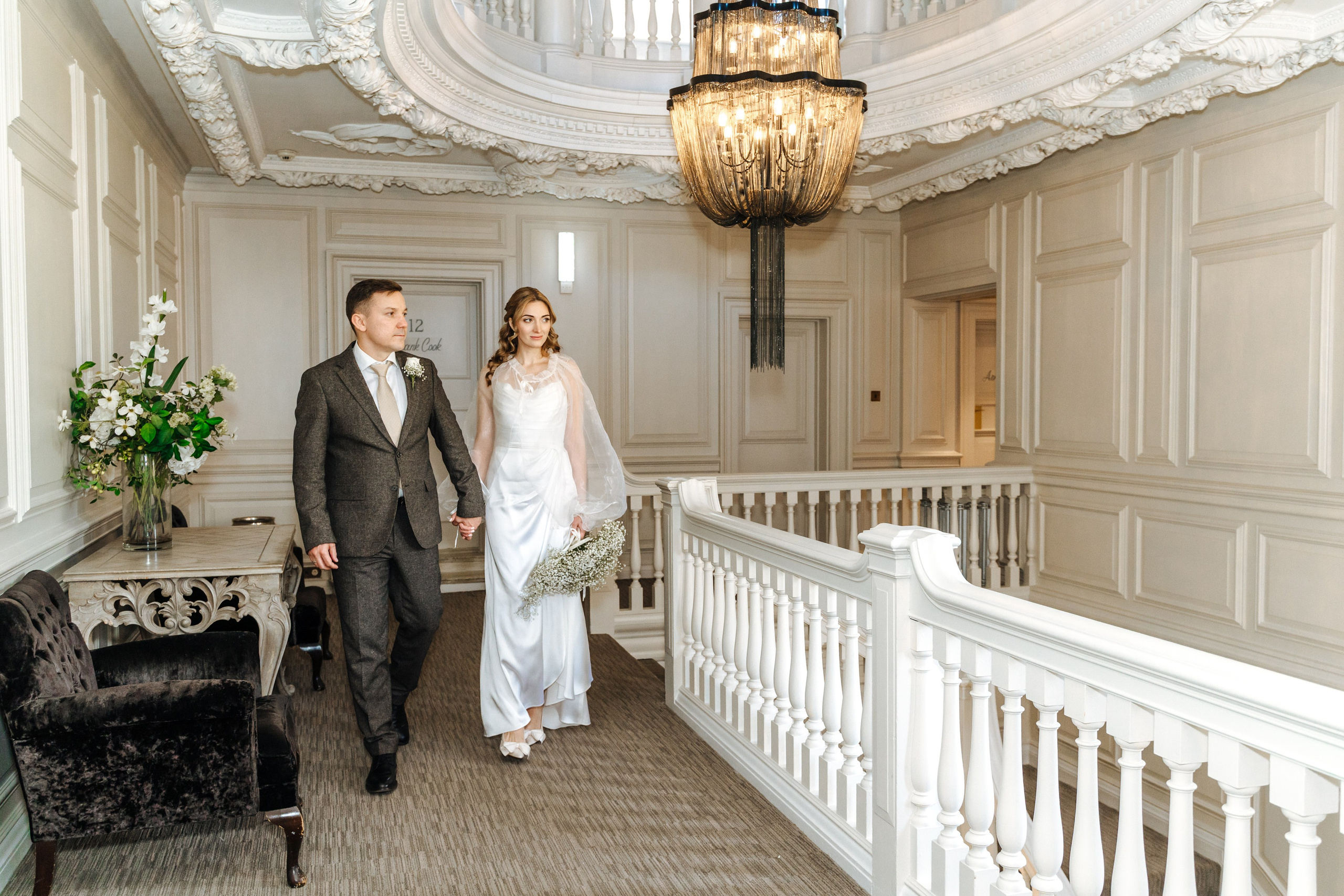 Andrey and Elena pose together in the elegant interior of Barnet Hill Hotel, featuring a grand staircase and classic architectural details.