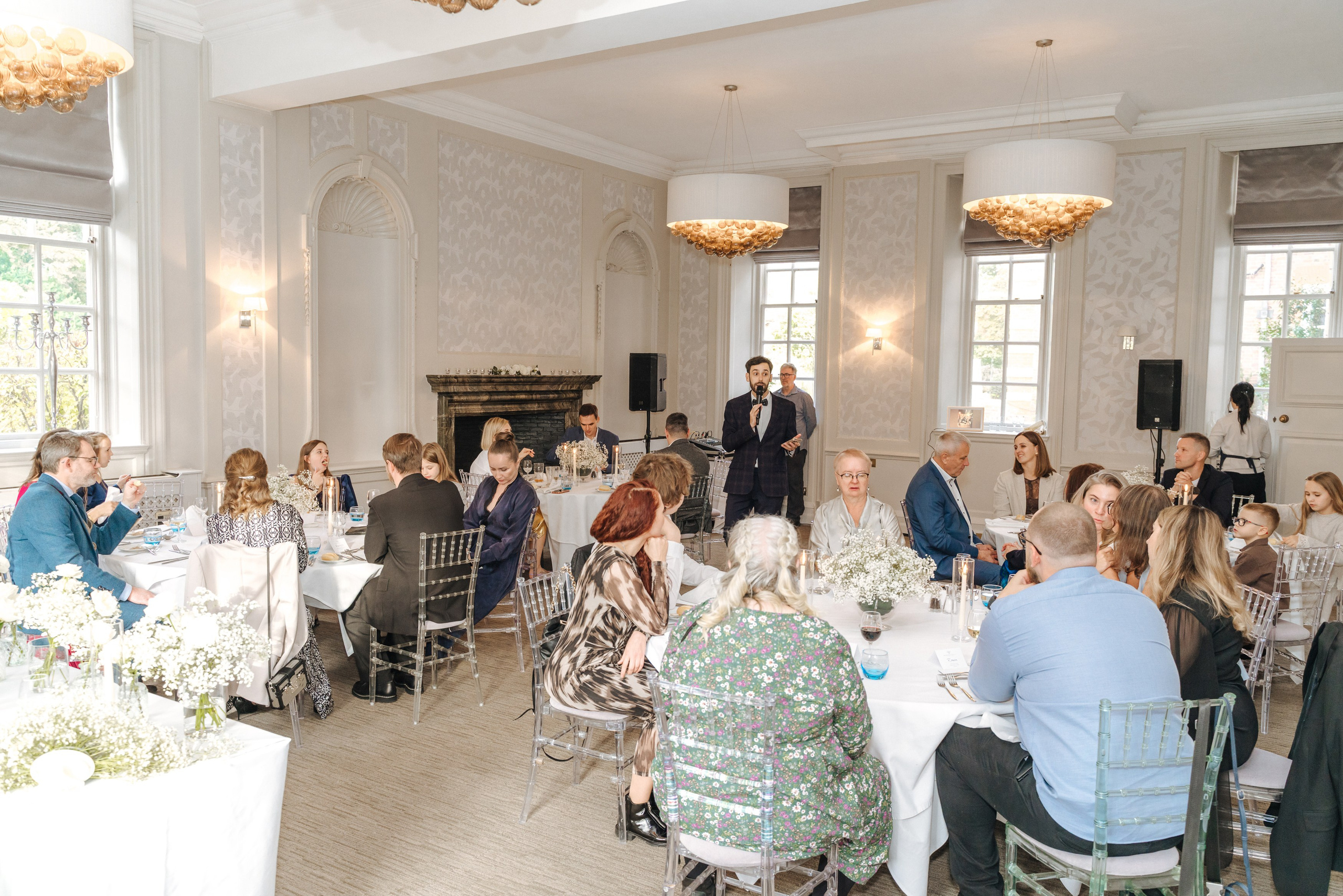 Family and friends celebrating Andrey and Elena's wedding reception in the elegant dining room at Barnet Hill Hotel.