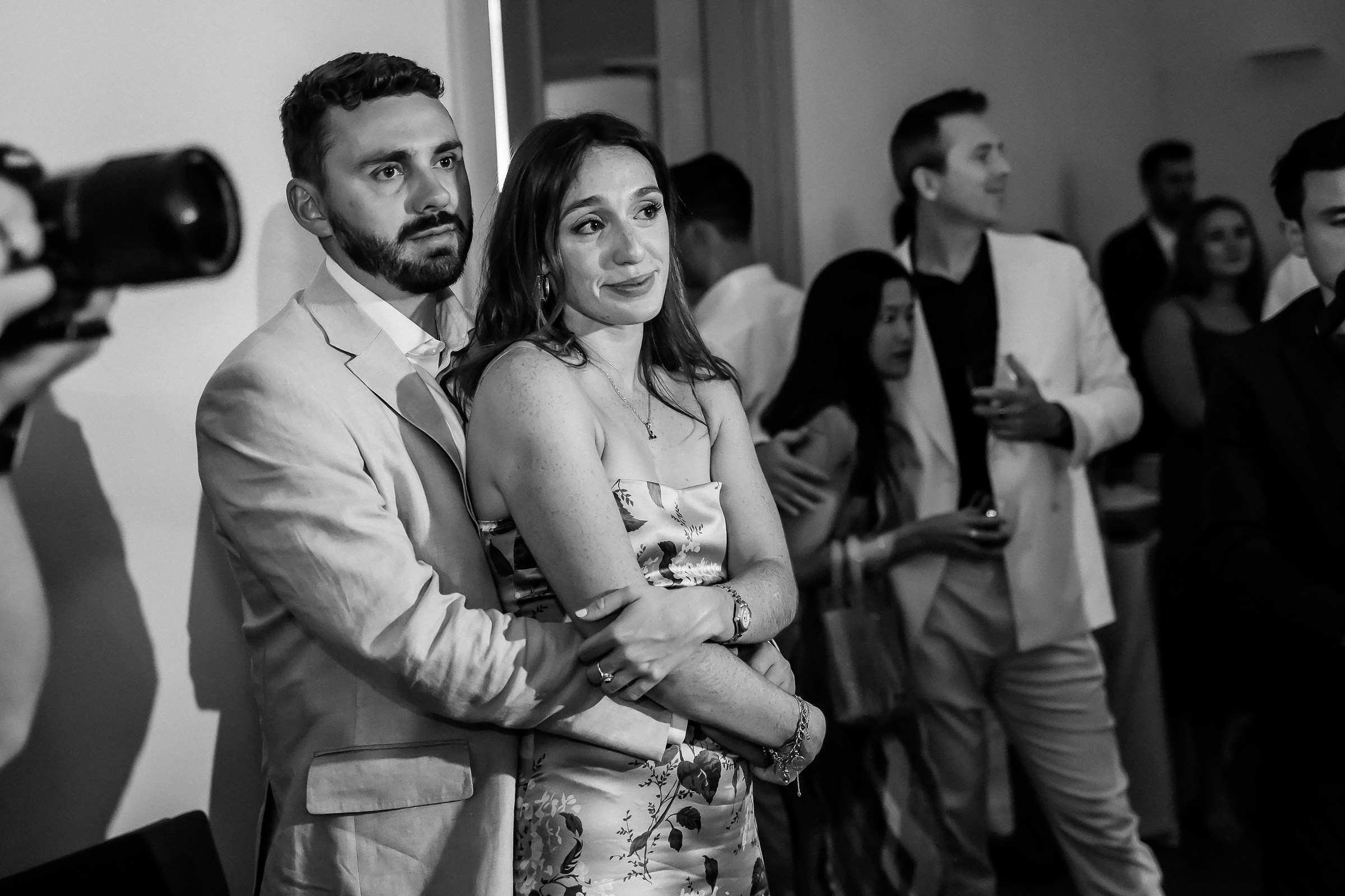 A couple holds each other close, watching the newlyweds with admiration during the reception.