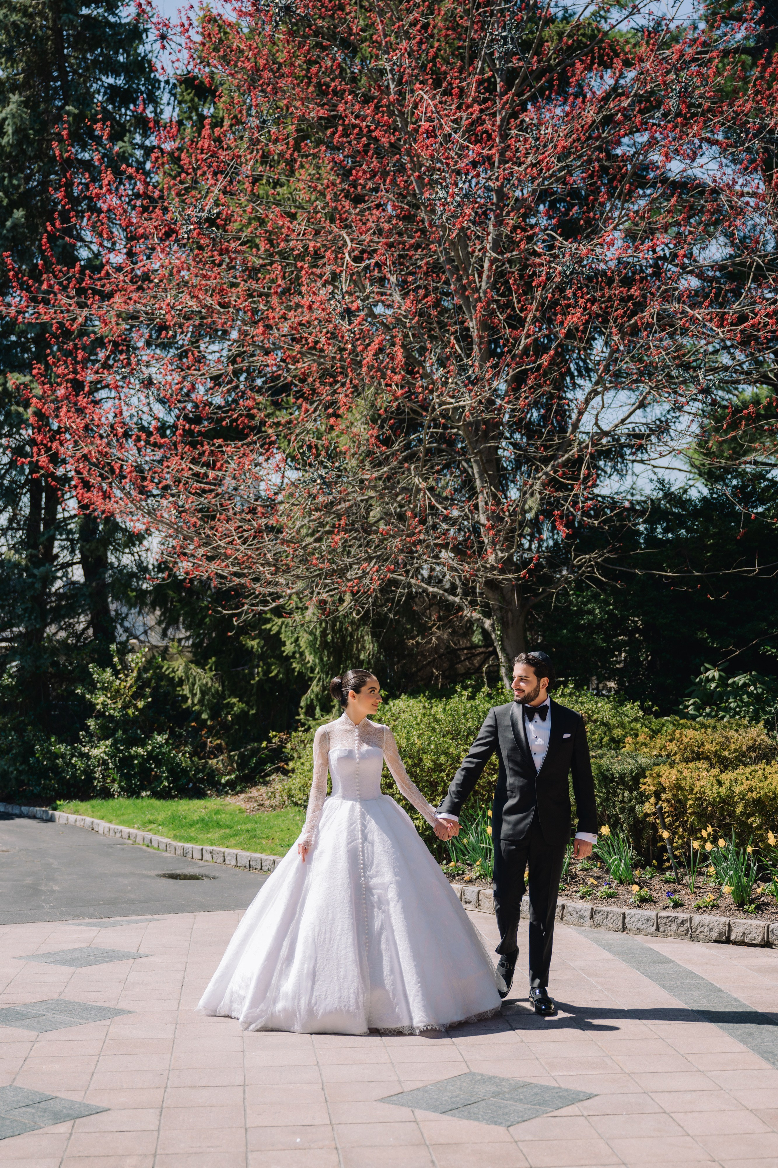 a bride and groom walking in front of a tree