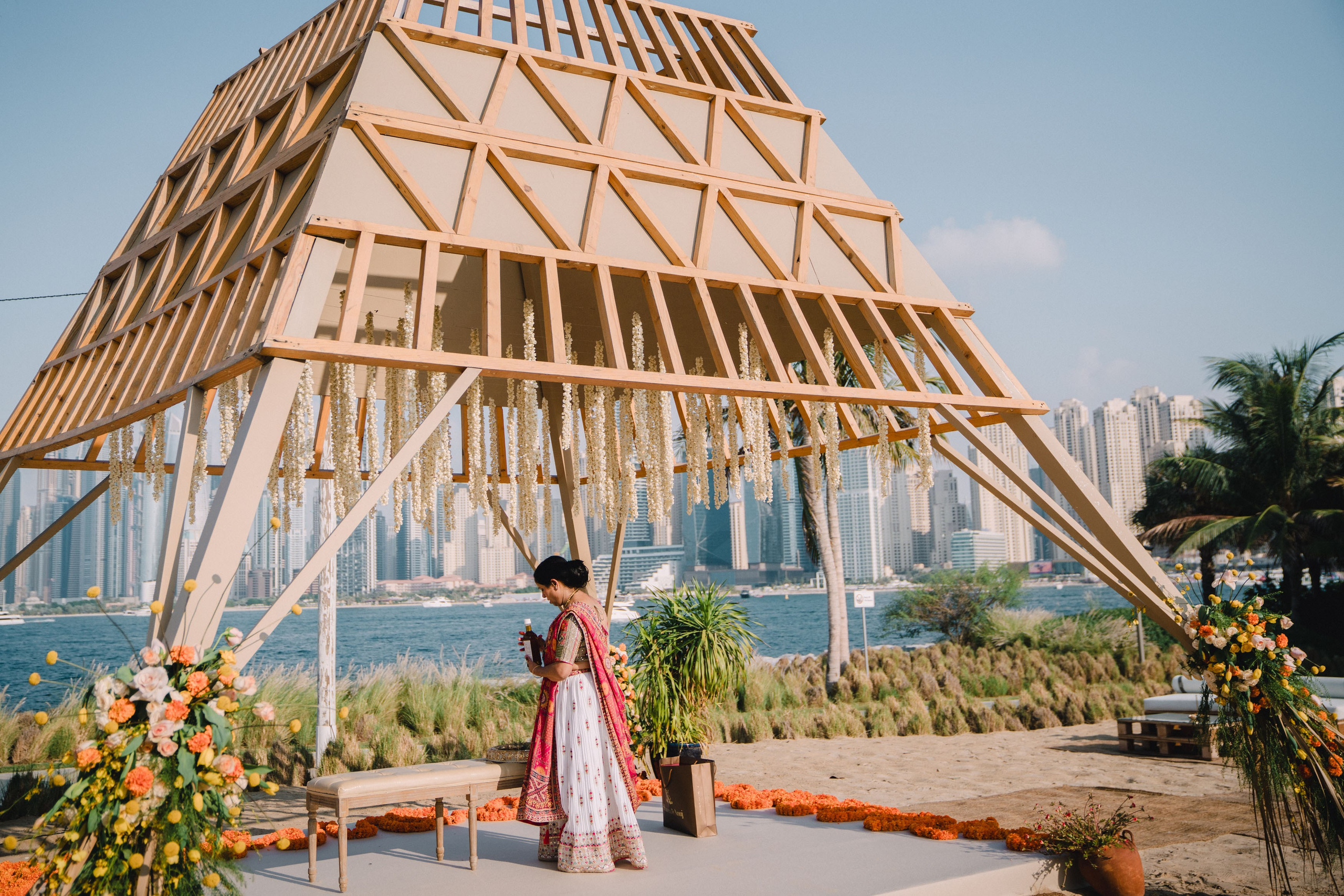 Indian lady dressed in red and white sari is preparing the turmeric ceremony