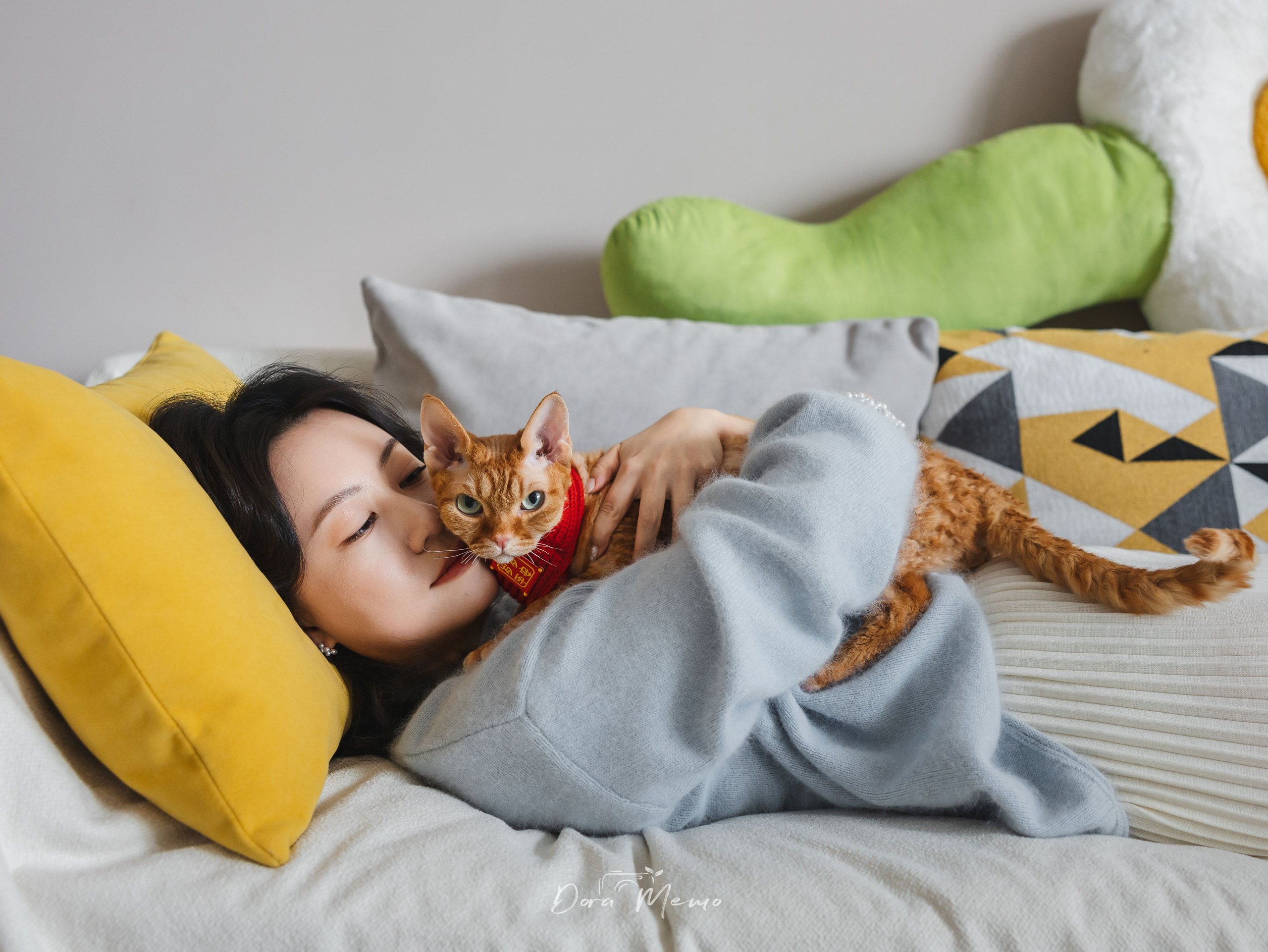 Owner cuddling her Devon Rex cat in a cozy bedroom during a pet photography shoot