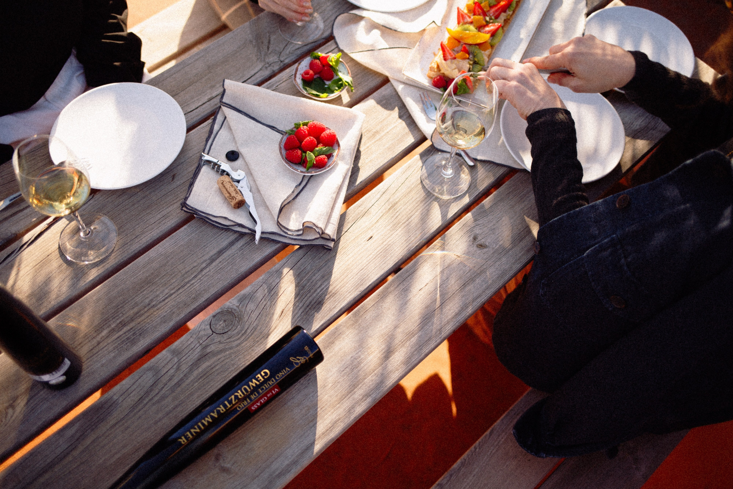 People gathered around a food table, sharing Vi de Glass and sweet treats