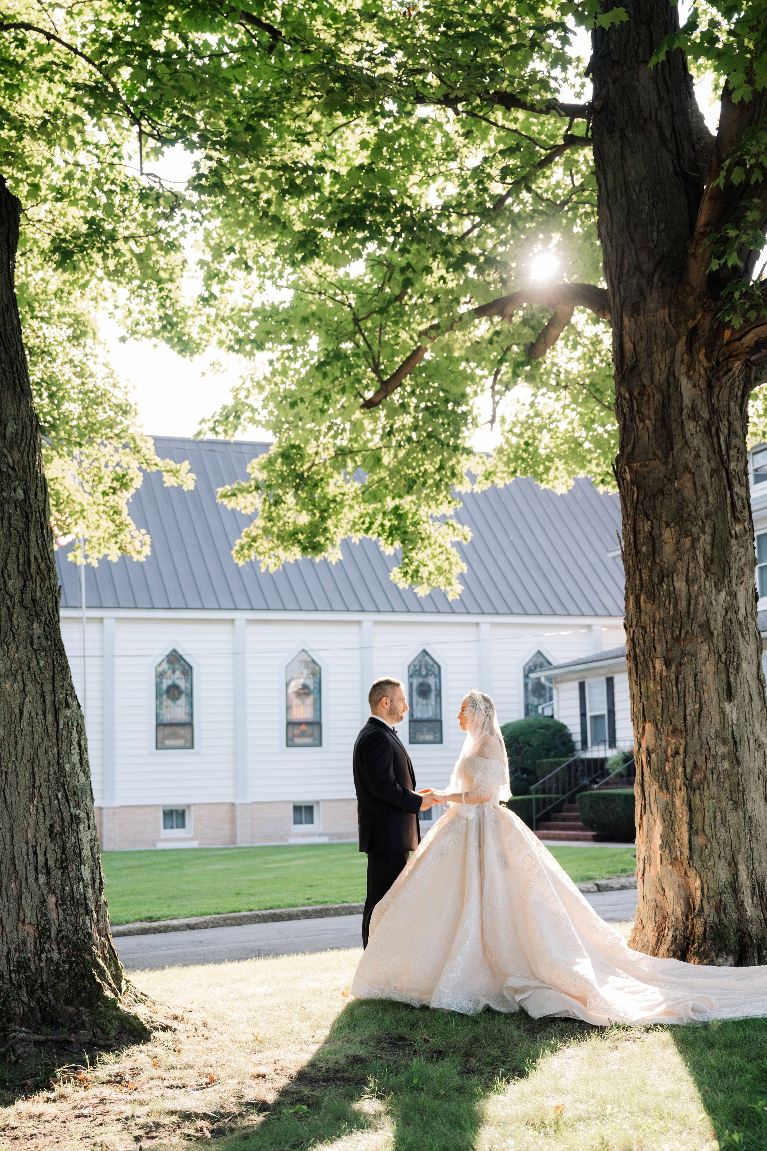 a bride and groom standing in front of a tree
