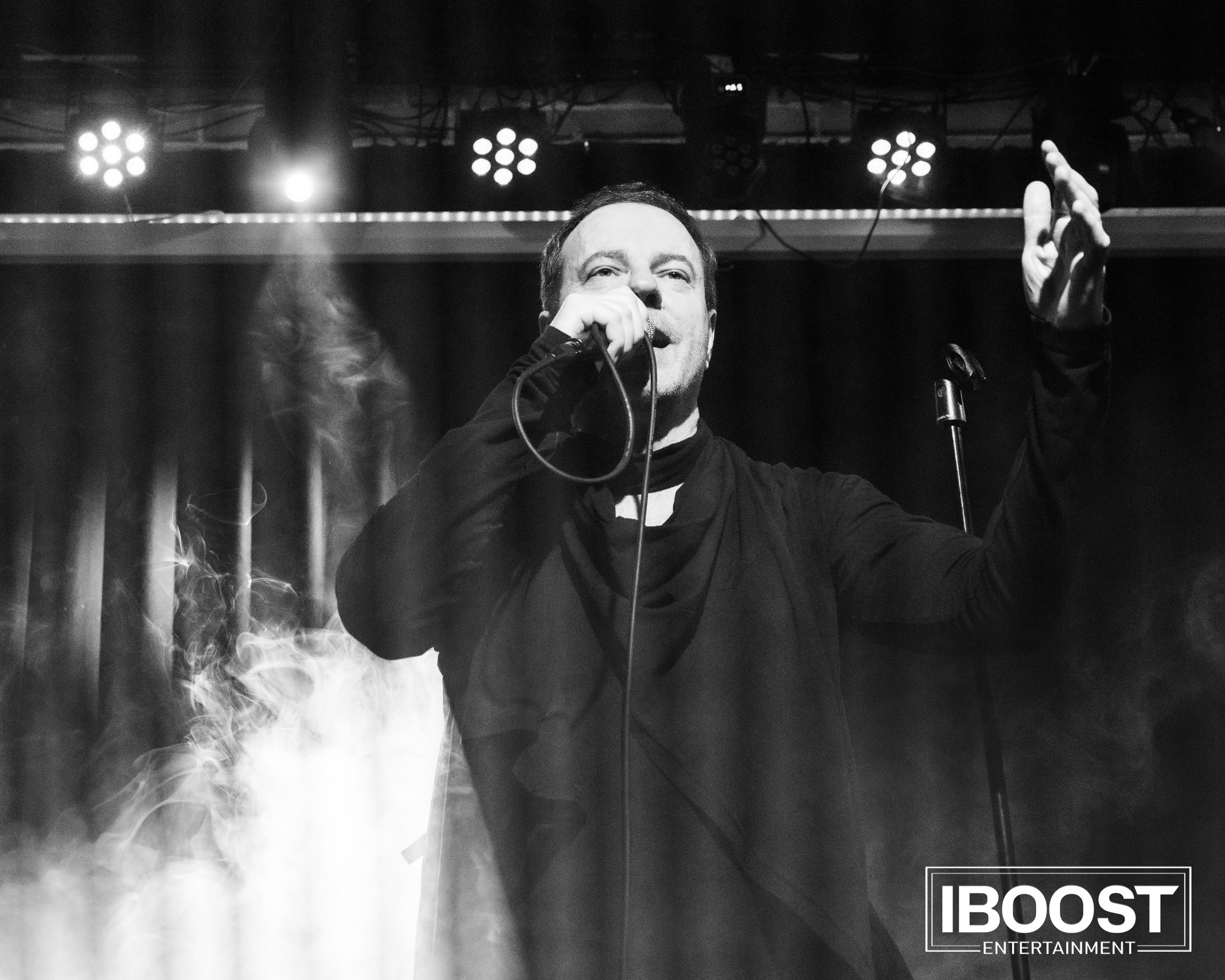 Black-and-white concert photo of the lead vocalist of Animal JazZ singing with both hands raised.