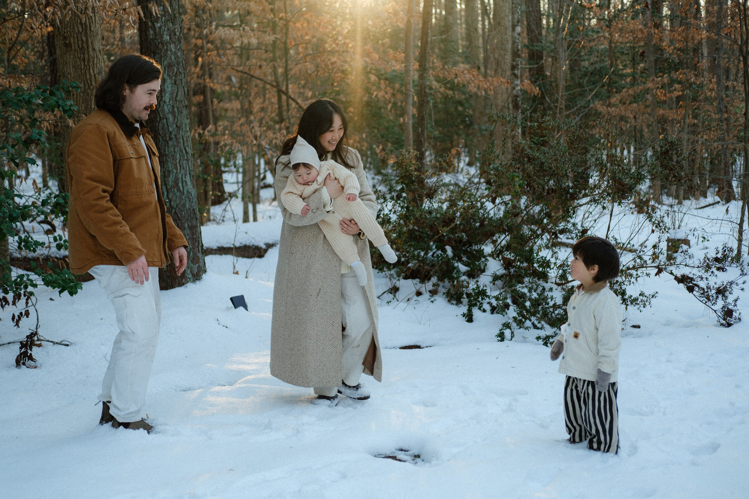 Group shot of a family standing in fresh snow, surrounded by trees near Richmond, VA — peaceful and full of light.