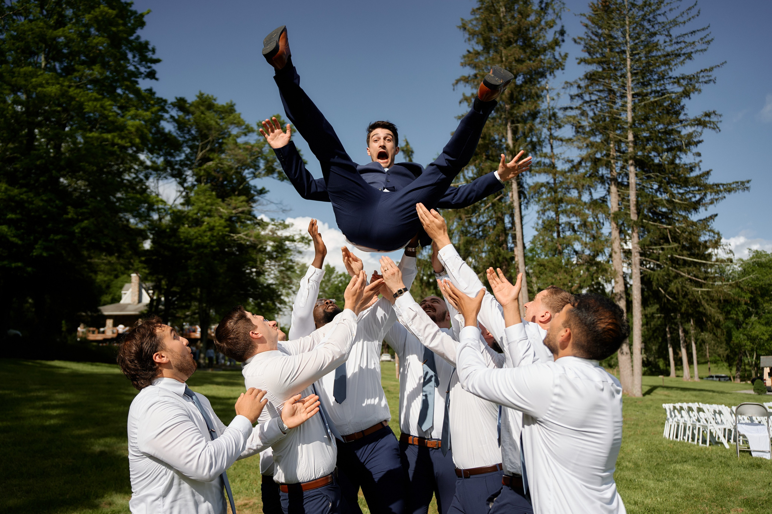Fun wedding photo of groomsmen lifting groom in the air outdoors in New Jersey