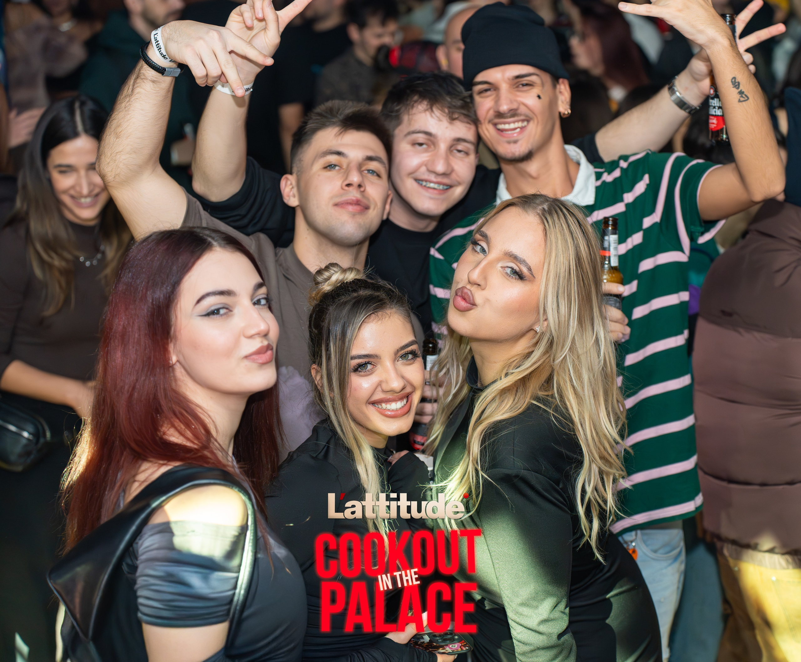 Group of young people posing and smiling at a party with drinks in hand.