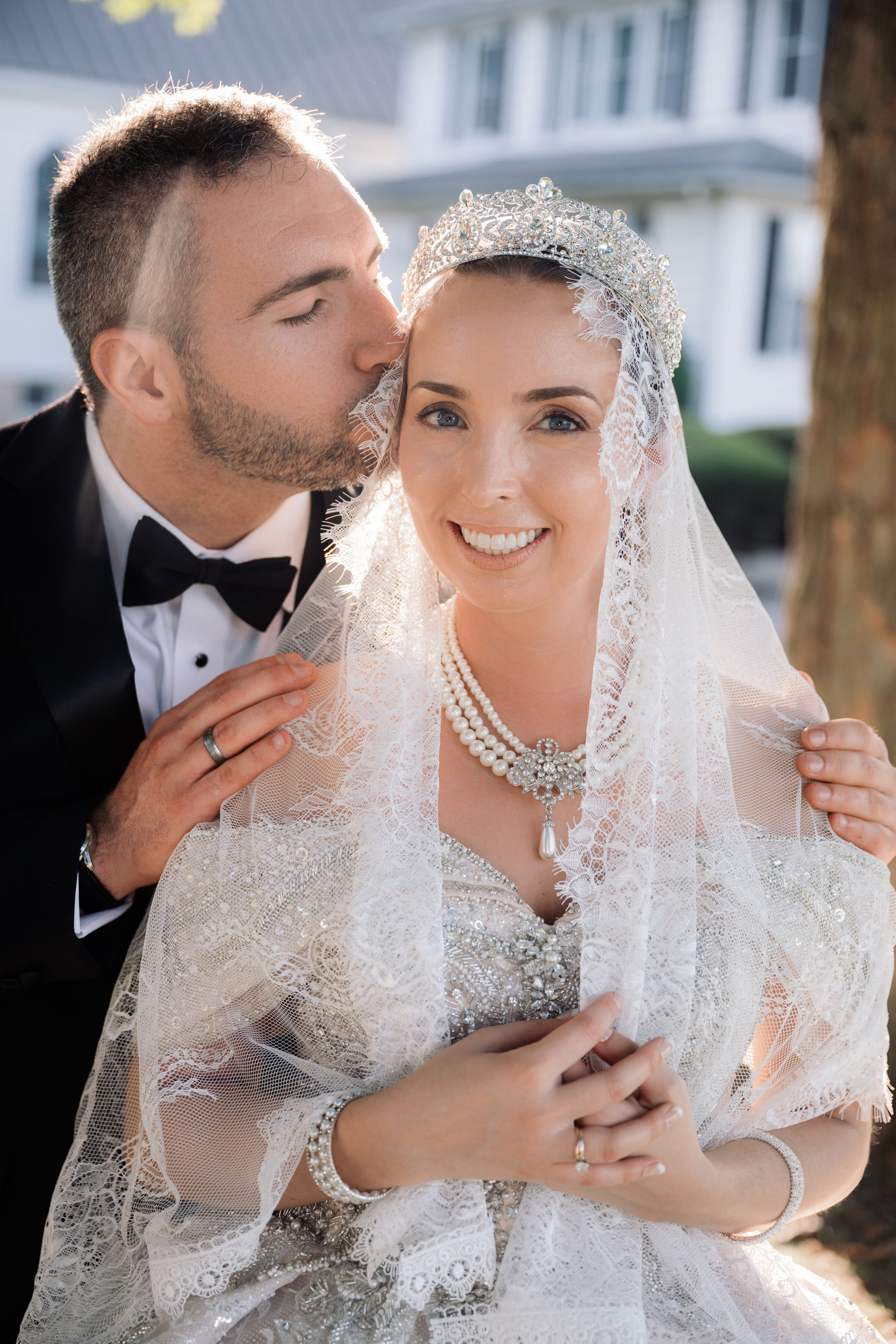 a bride and groom kissing in front of a house