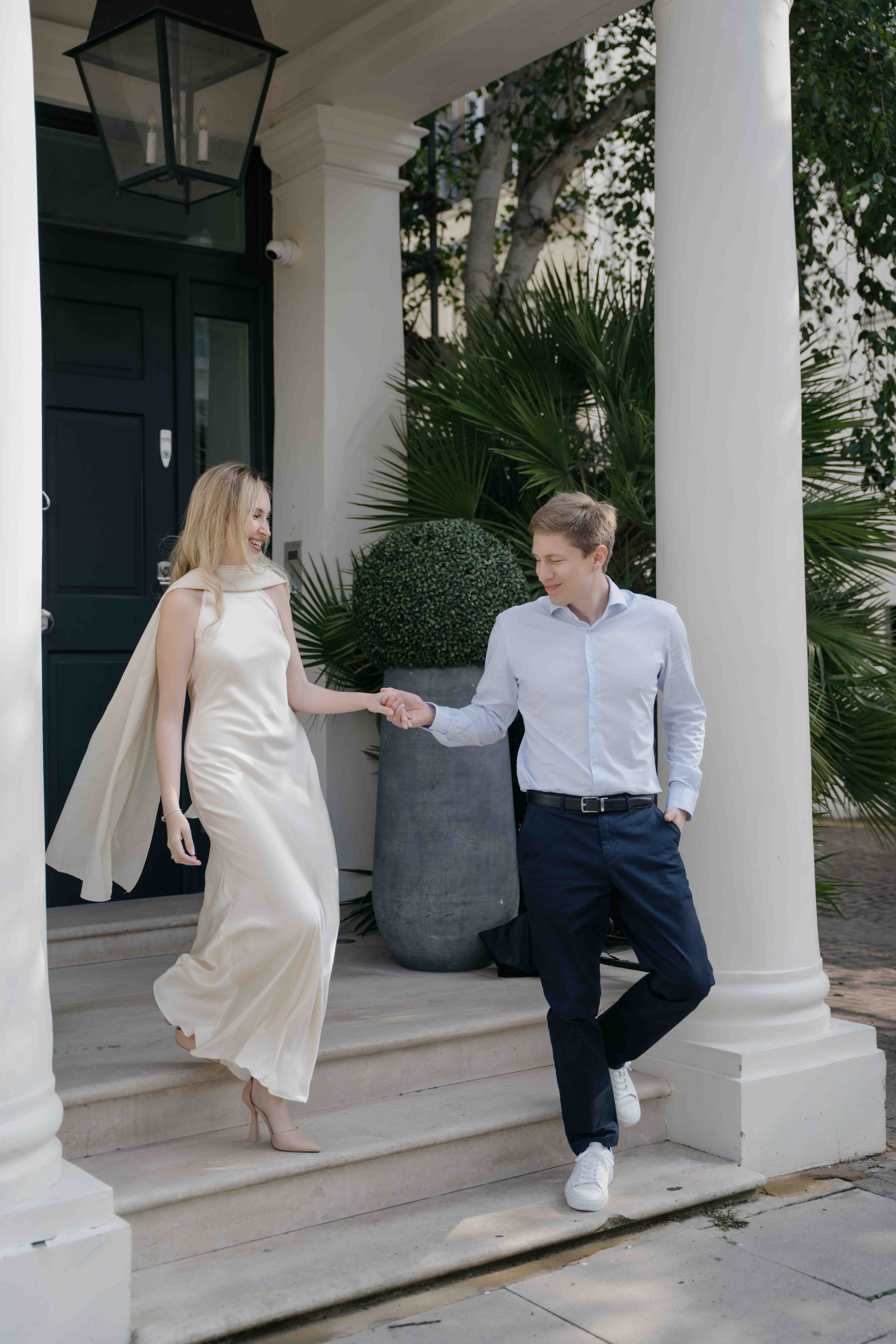 Couple walking down steps near white columns in South Kensington London engagement photoshoot