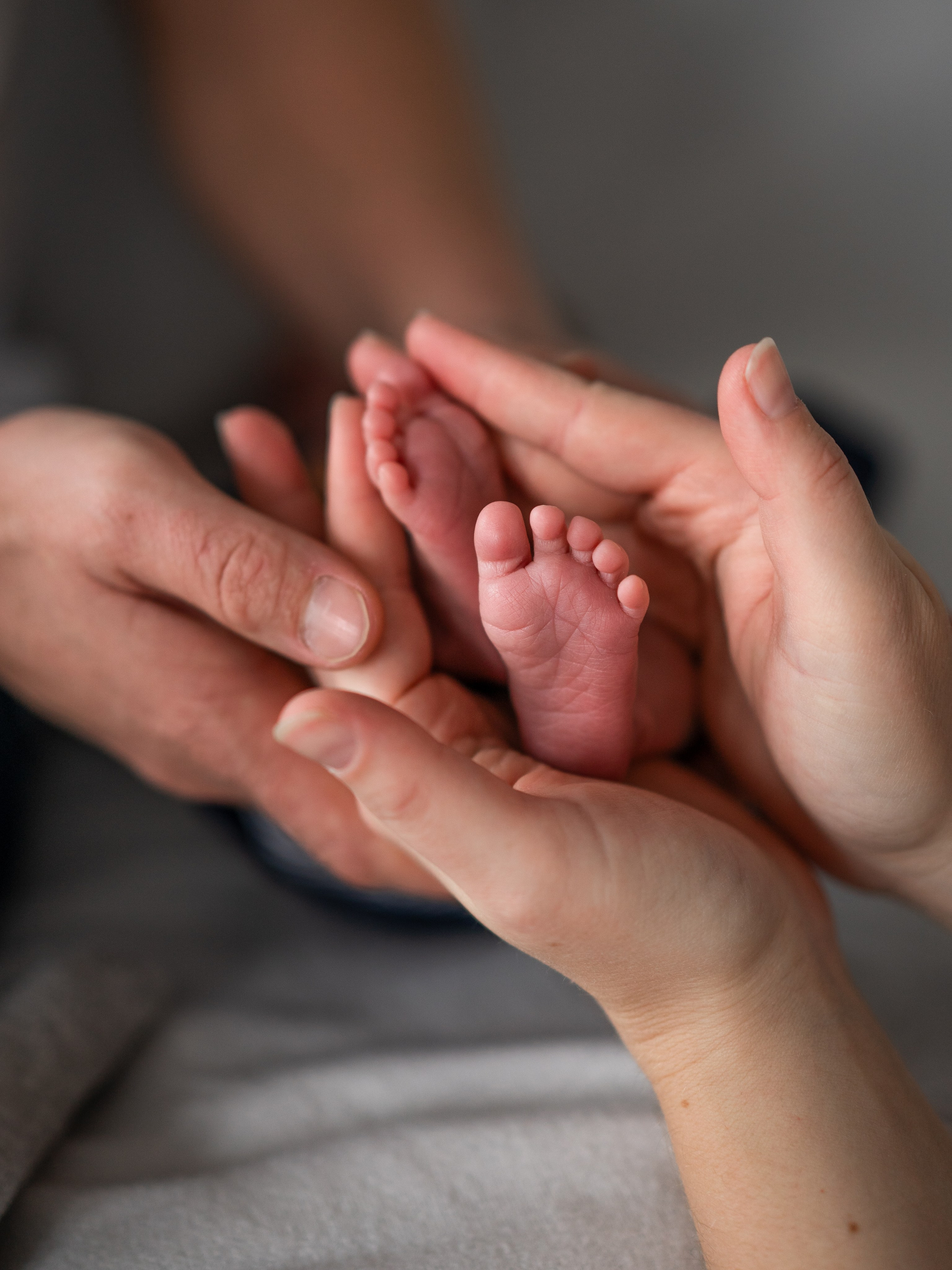Liebevolle Hände der Eltern umschließen die winzigen Füßchen ihres Neugeborenen