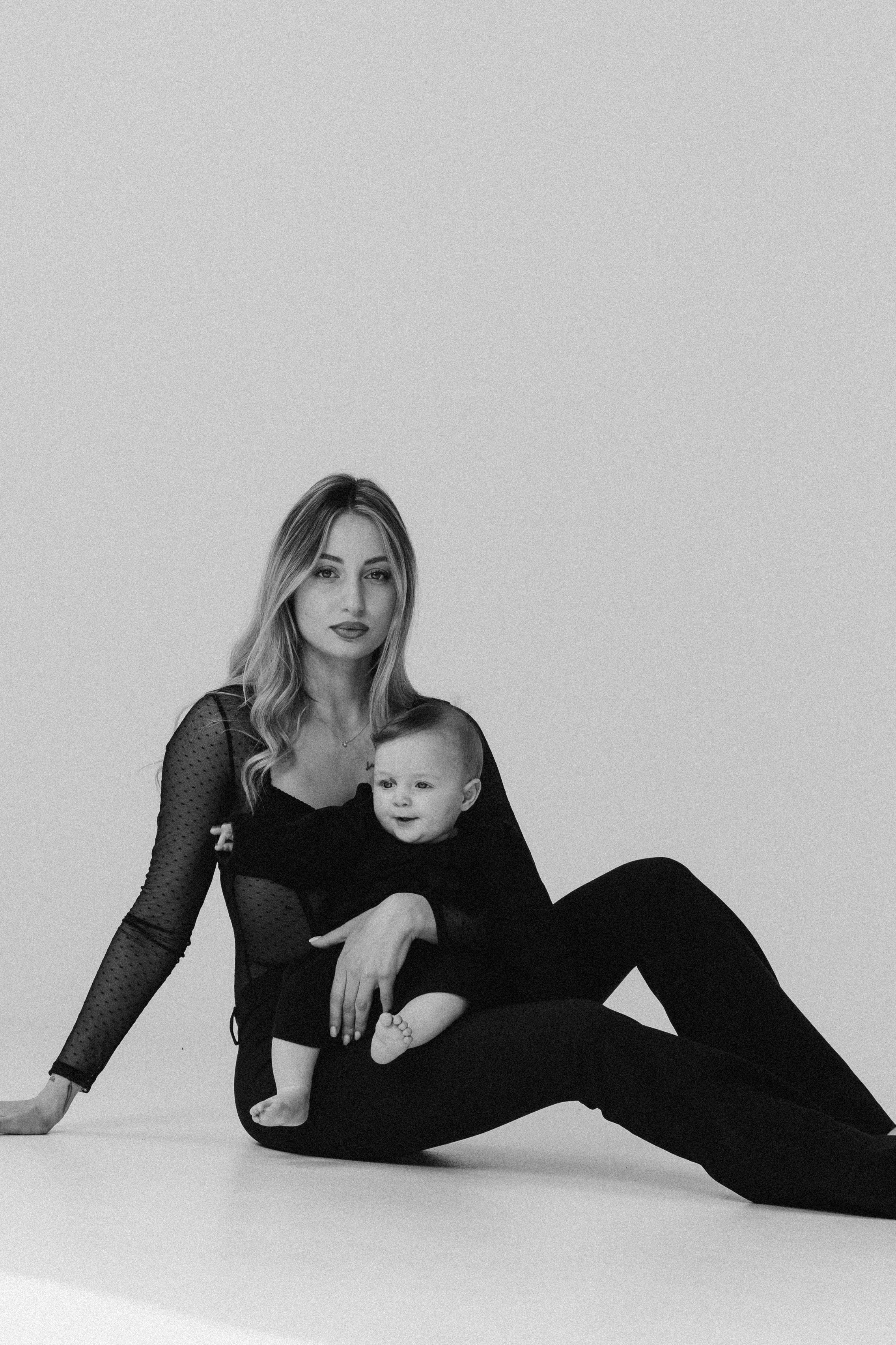 Madre seduta con il suo bambino in grembo durante una sessione fotografica di famiglia a San Marino. Un momento intimo che trasmette calma, presenza e connessione emotiva.