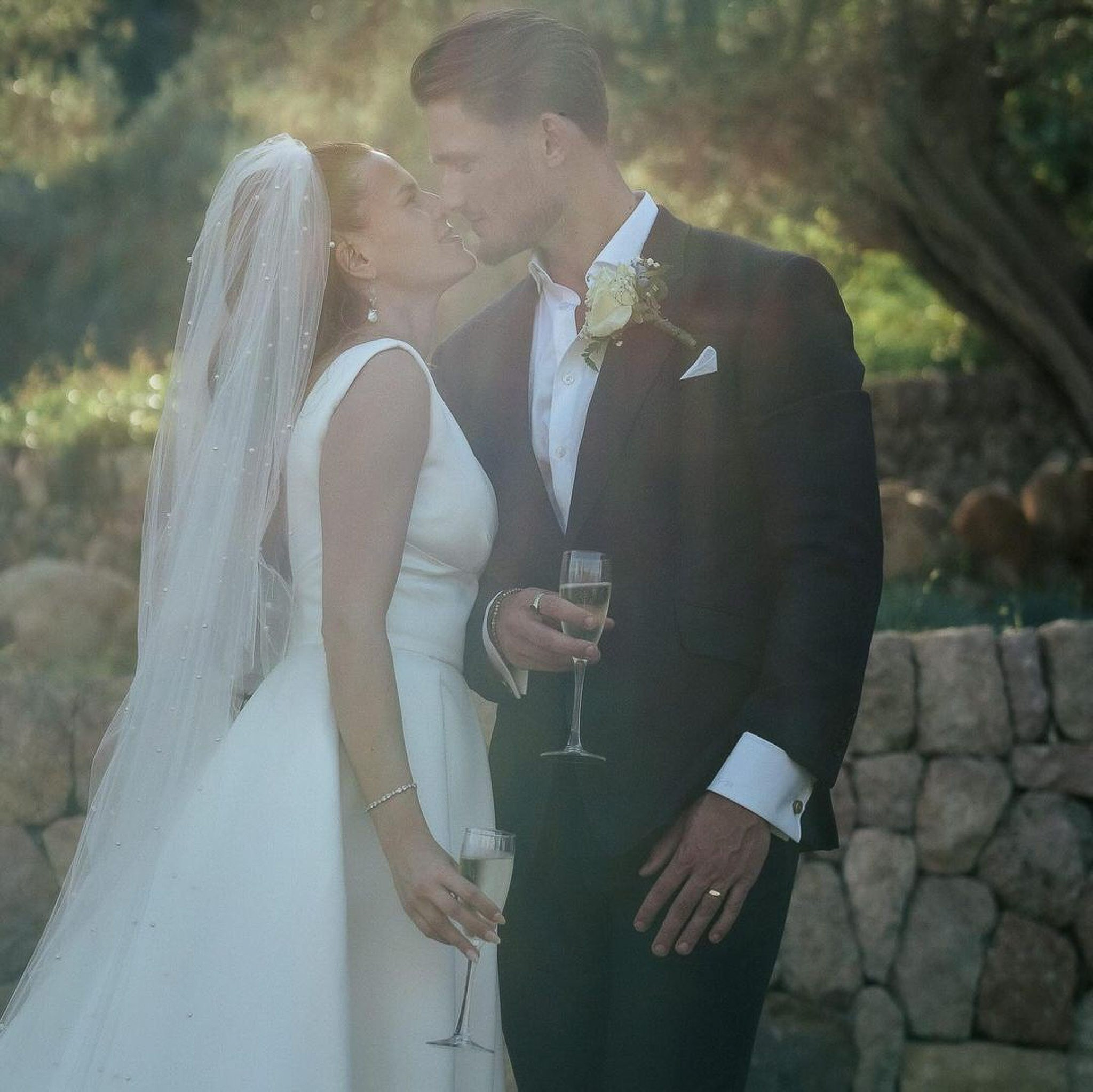 Newlyweds sharing a kiss with champagne in hand at their Mallorca wedding celebration