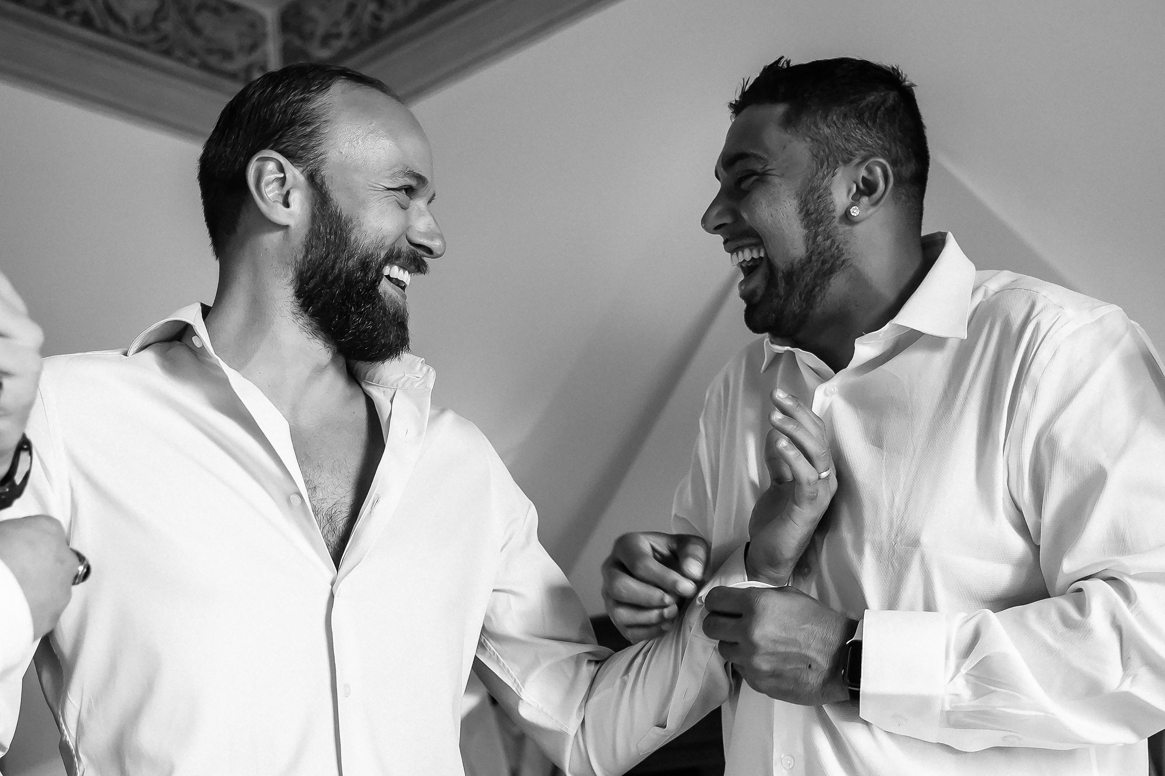 Close-up of groomsmen sharing a joyful moment while dressing.