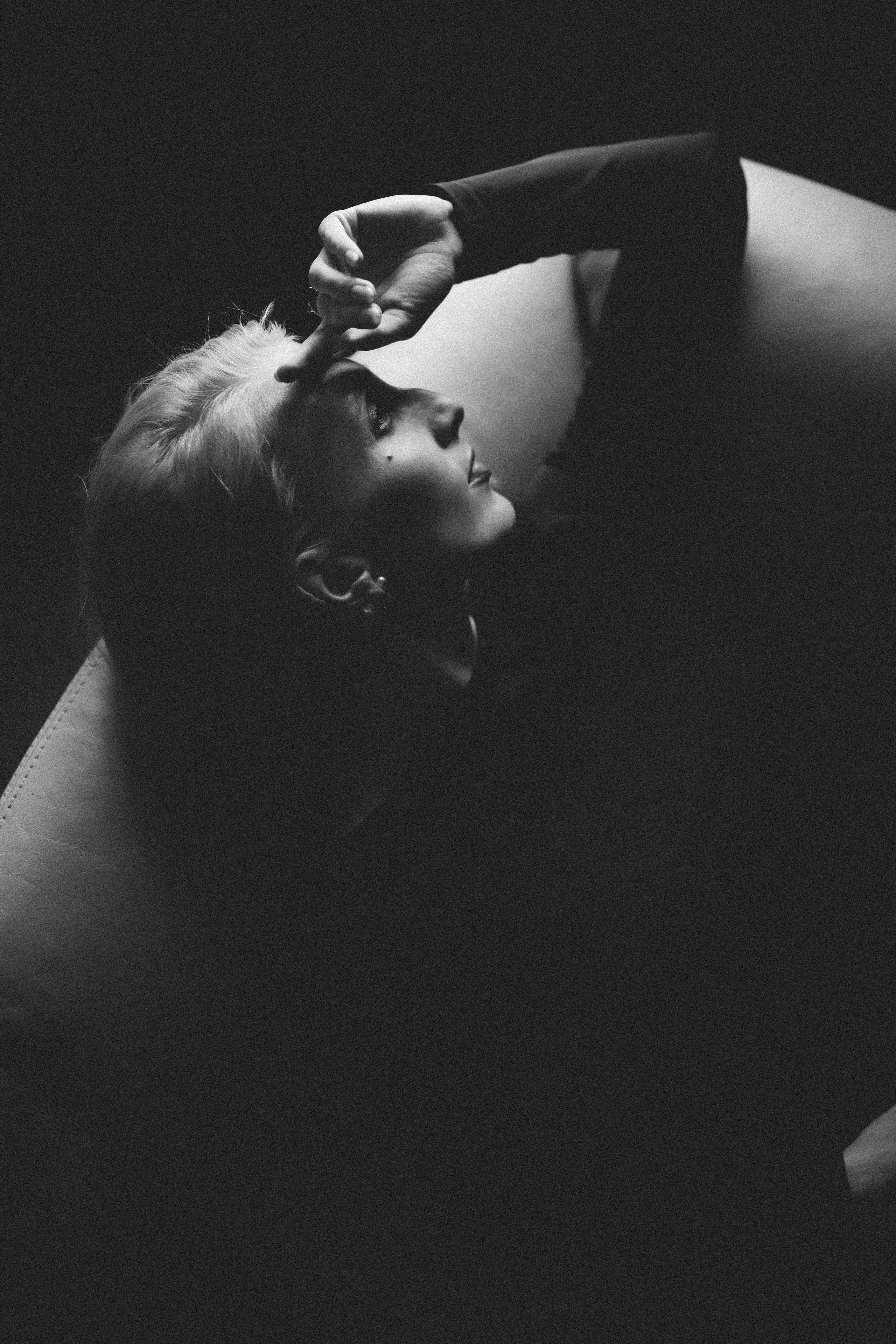 Die Frau wirkt elegant und feminin, aber auch nachdenklich und zurückgezogen. Das Schwarz-Weiß-Format unterstreicht die klassische, zeitlose Ästhetik des Bildes.