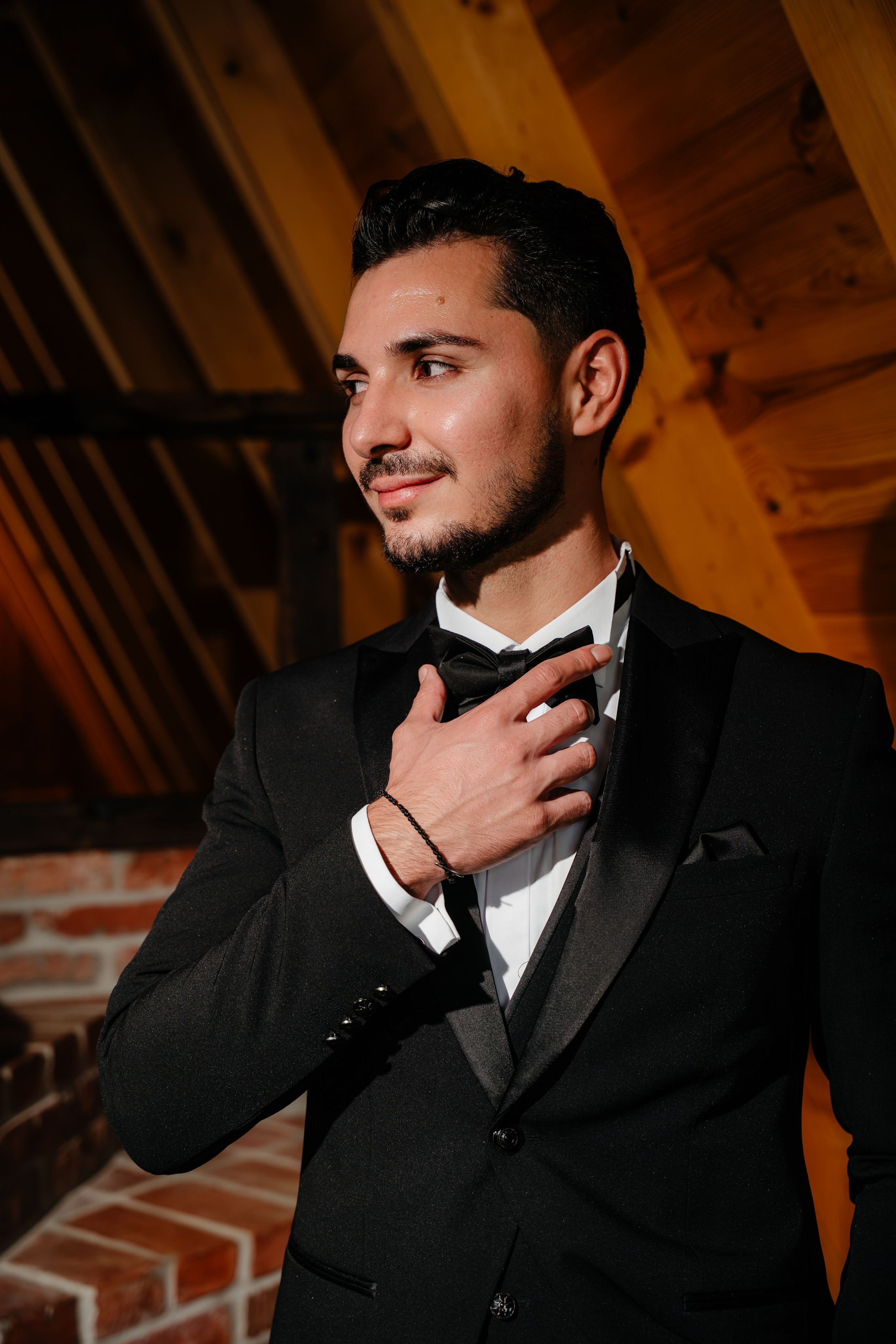 Portret de mire ajustându-și papionul în interiorul modern de la Cabana Masiv.