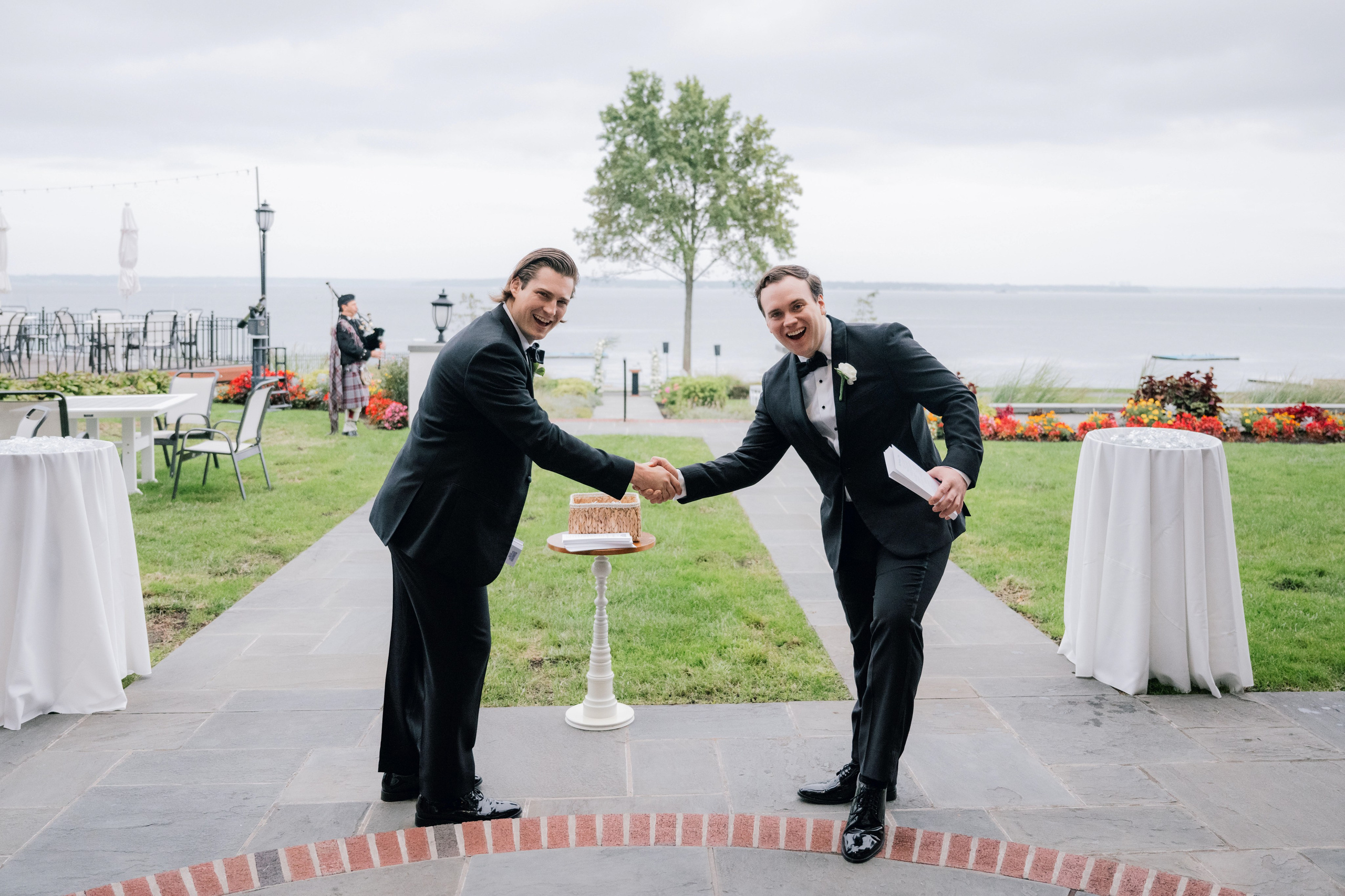 two men in suits are shaking hands at a wedding