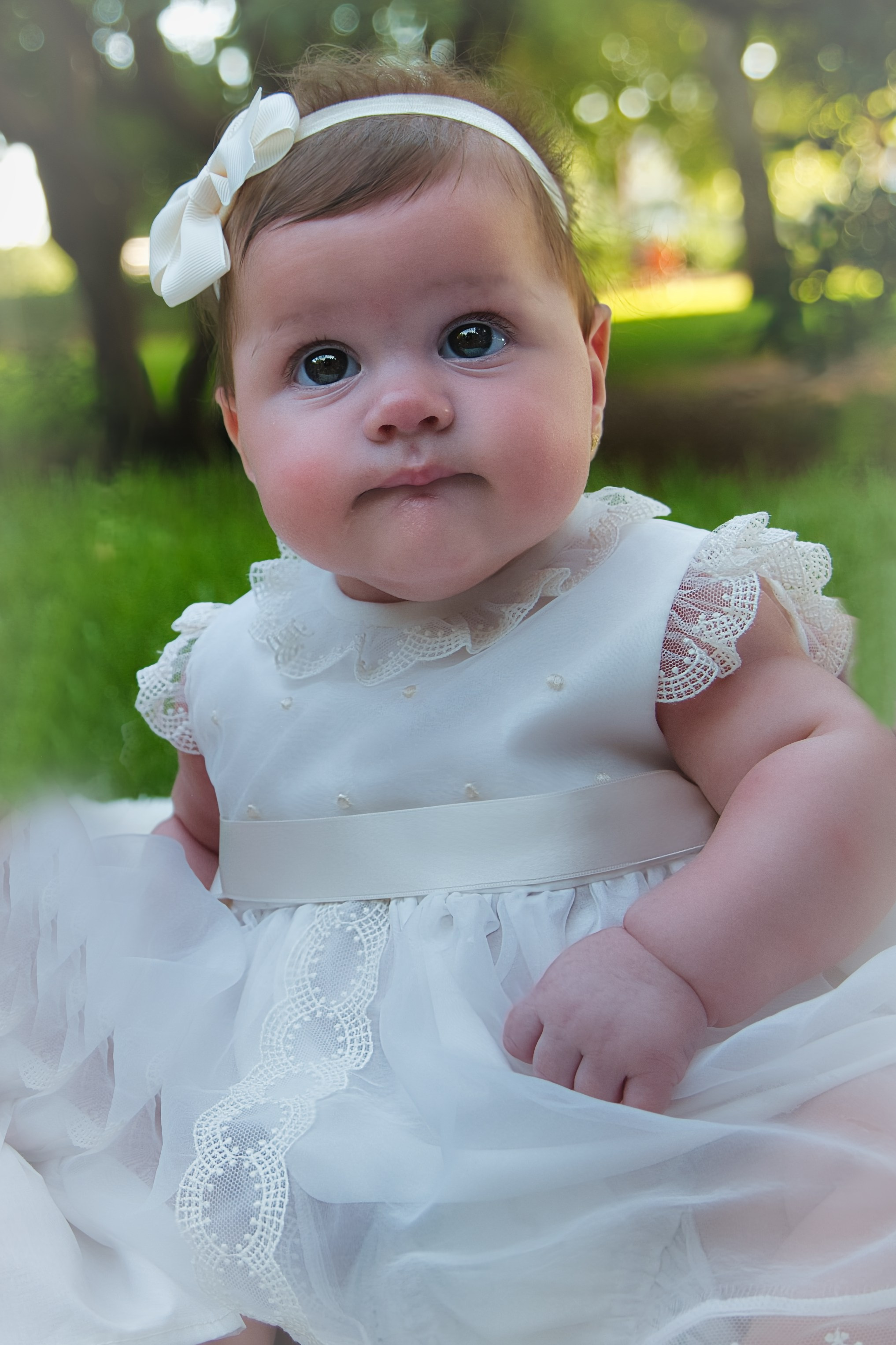 Niña con su vestido de bautizo blanco sonriendo dulcemente.