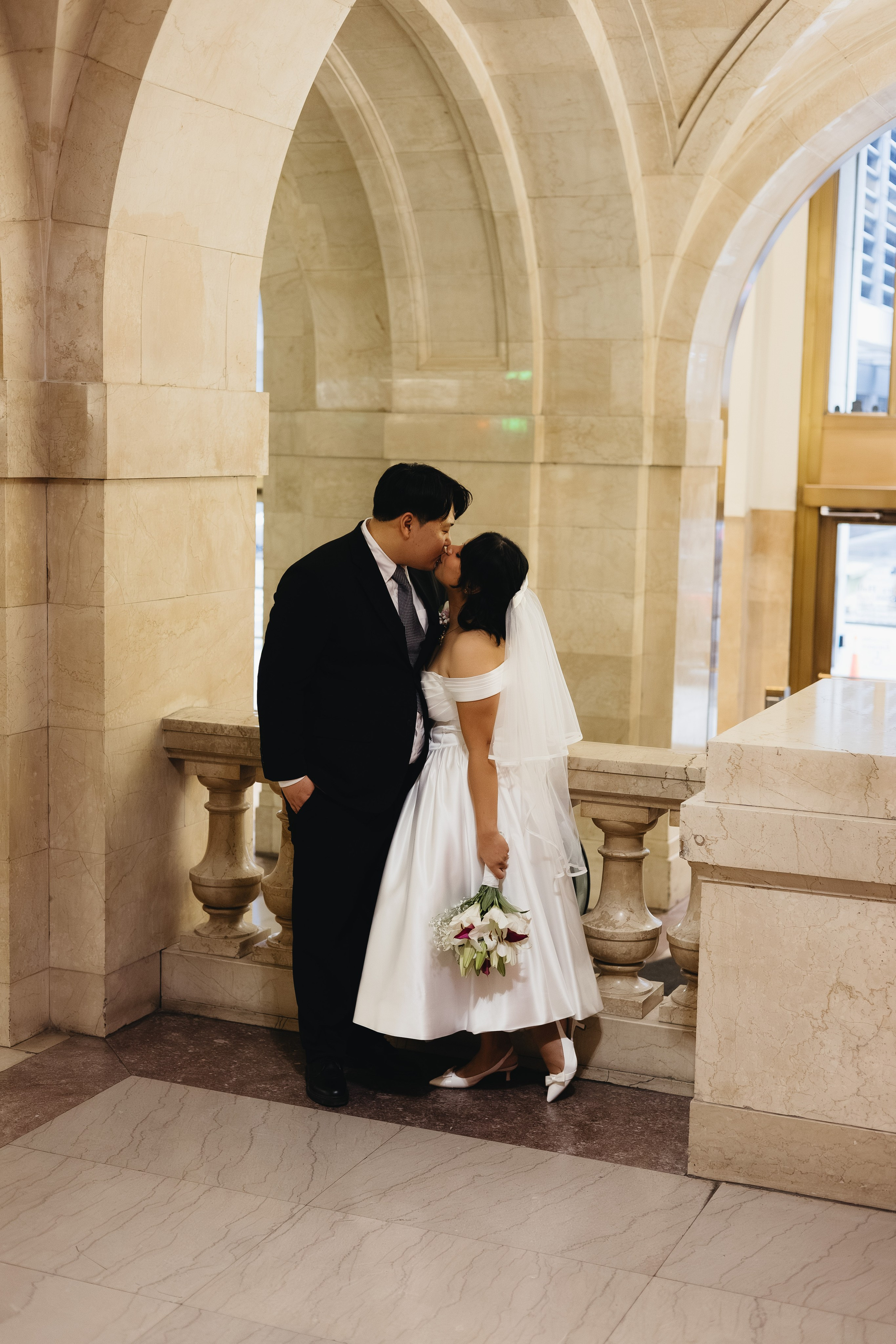 Couple kissing inside Chicago City Hall against a granite wall