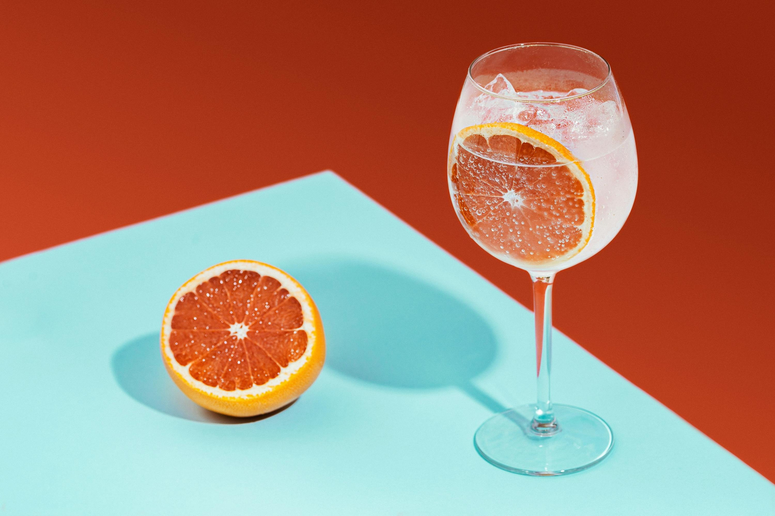 Creative drink photography of orange cocktail on colourful background, photographed by Jay Soundo for bar and restaurant content