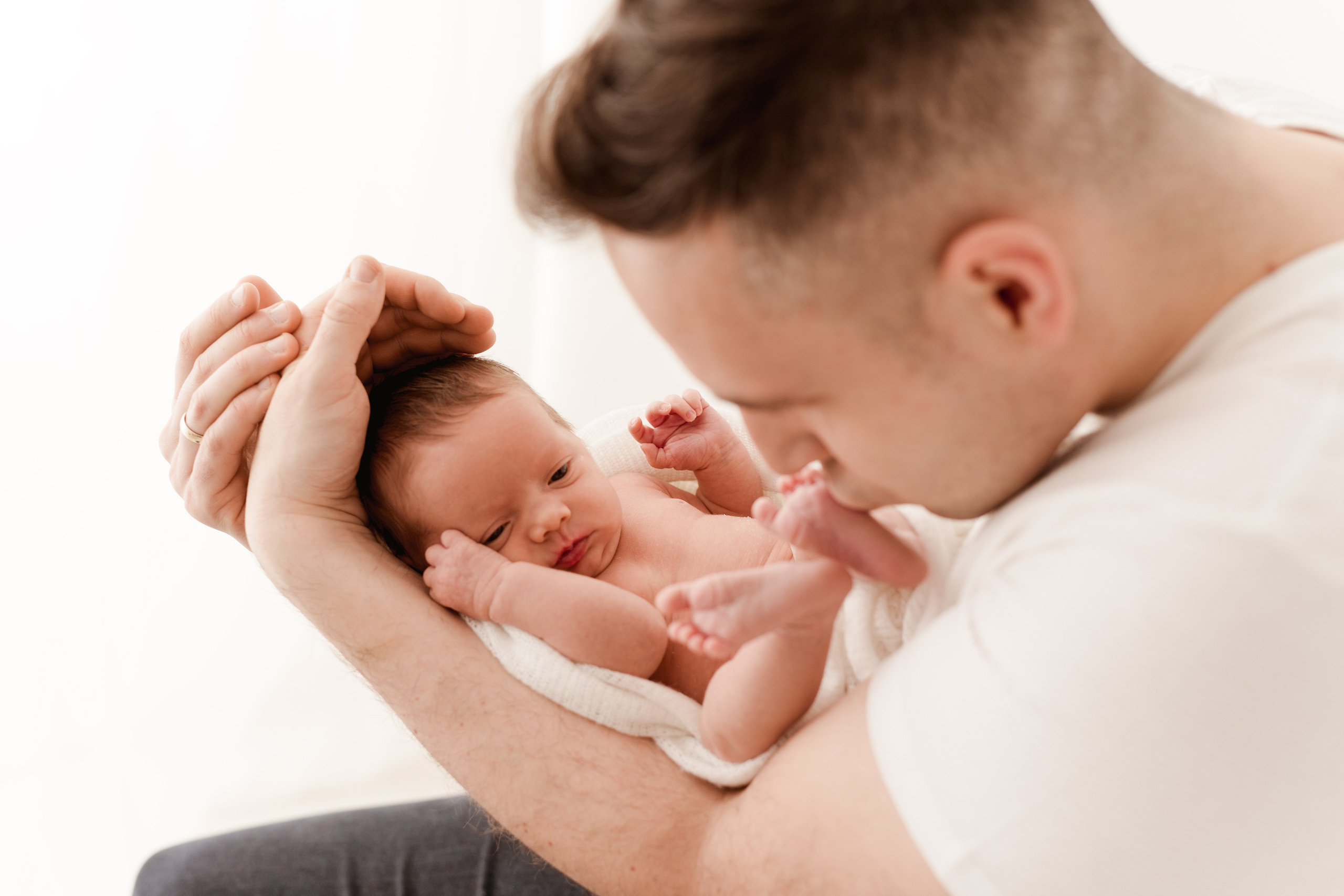 Malutka córeczka w silnych obejmach taty. Sesja noworodkowa w Łodzi.