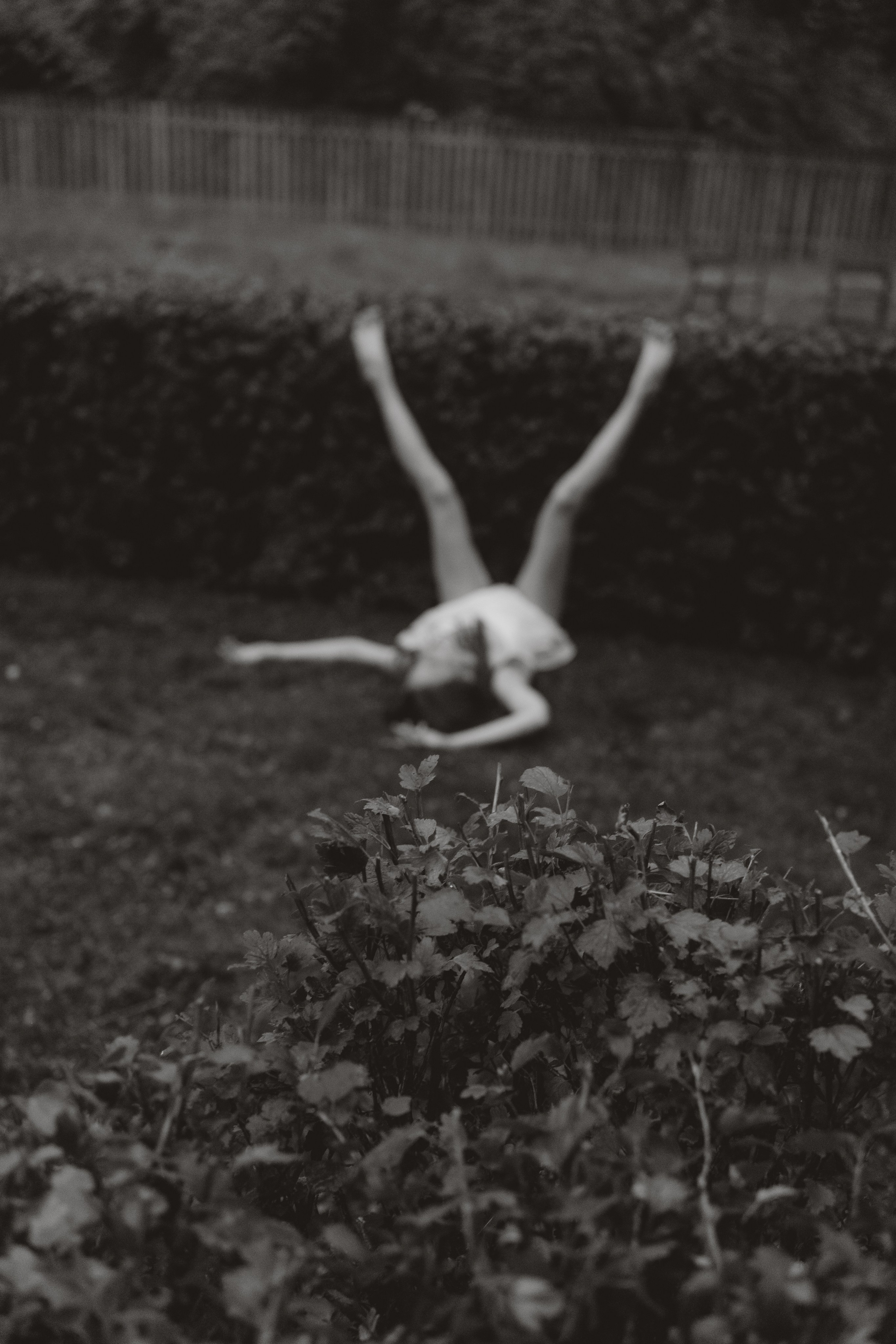 Fine art portrait of a woman lying on grass with raised legs, black and white photograph