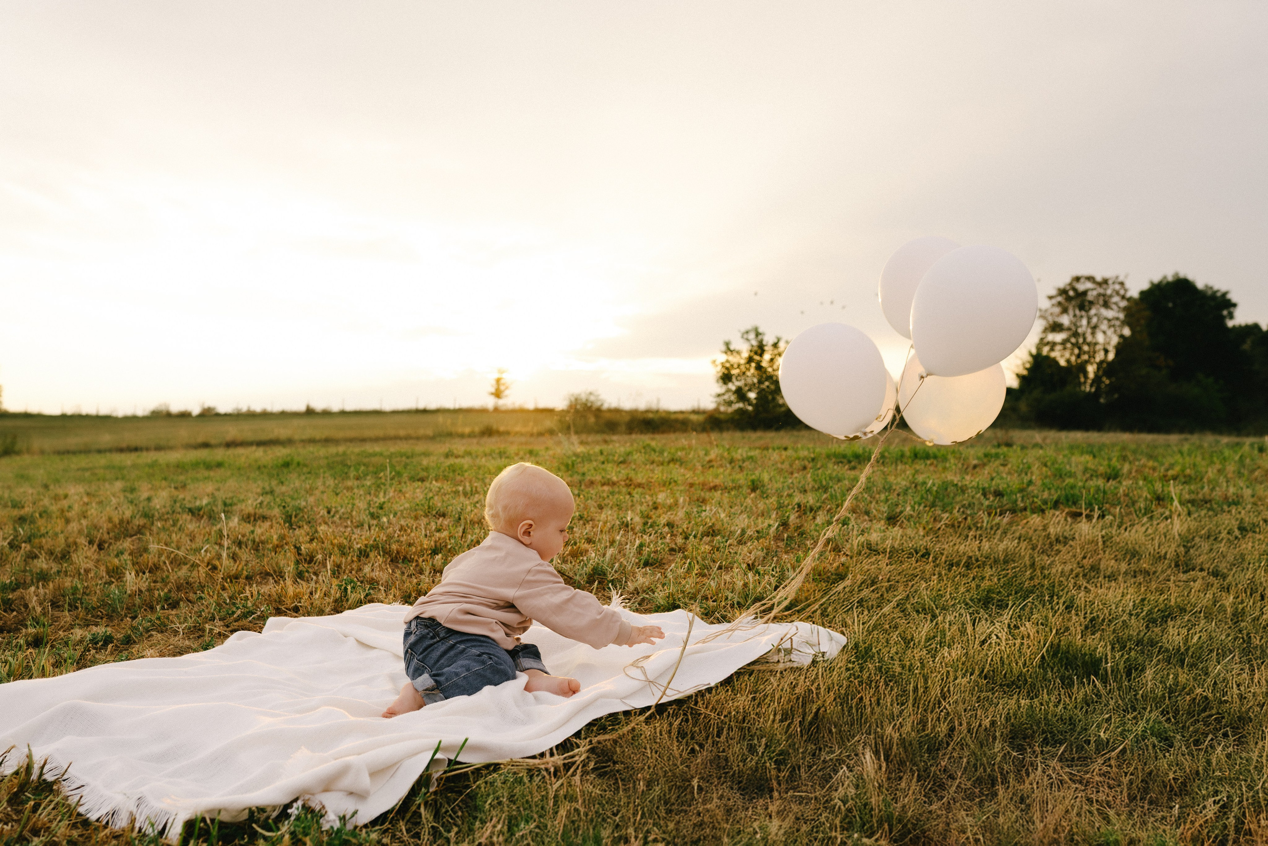 1-jähriger Junge, der bei einem Fotoshooting im Freien mit Luftballons spielt