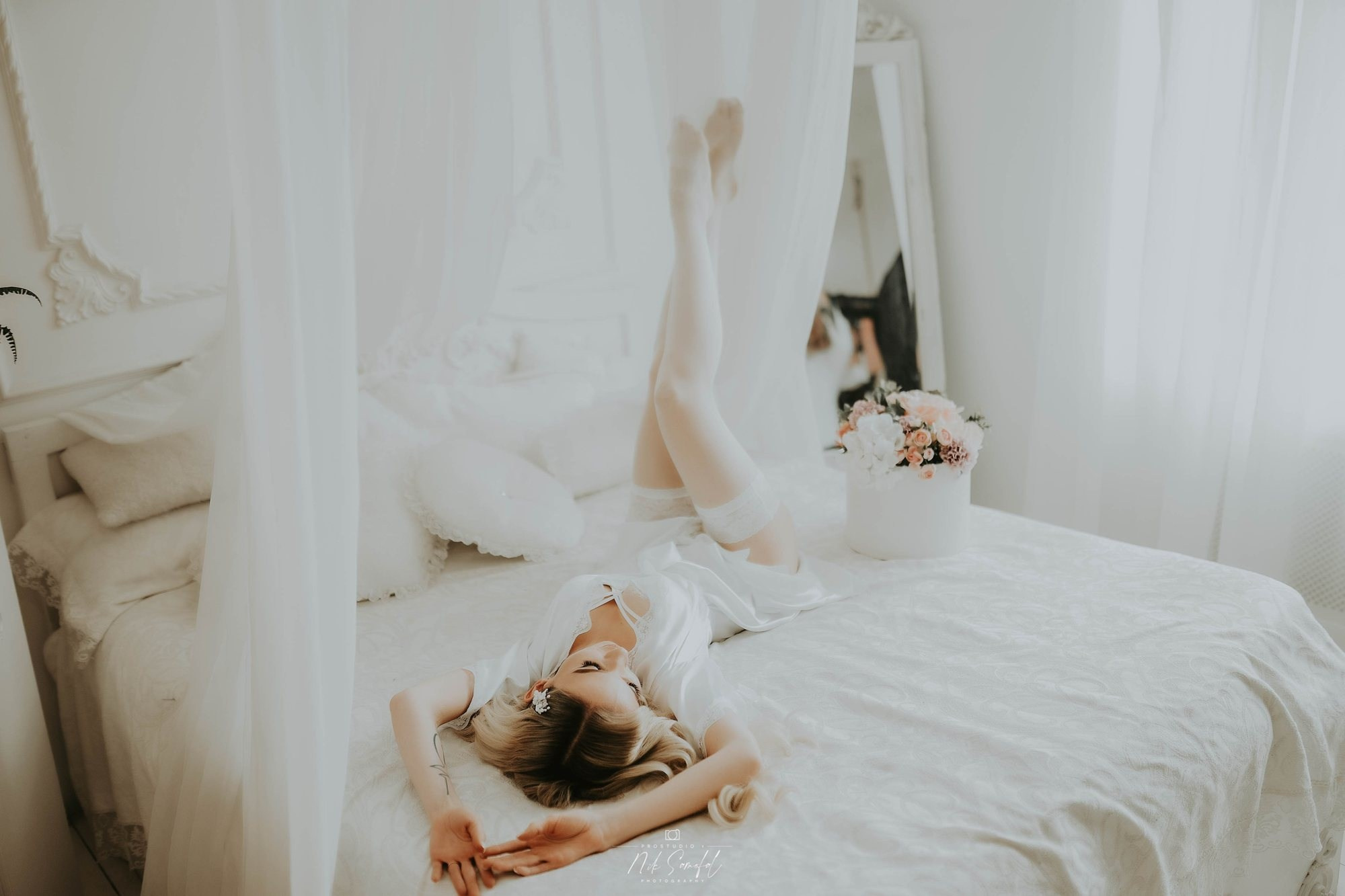 Bridal morning portrait Miami — bride relaxing on a white bed in soft light