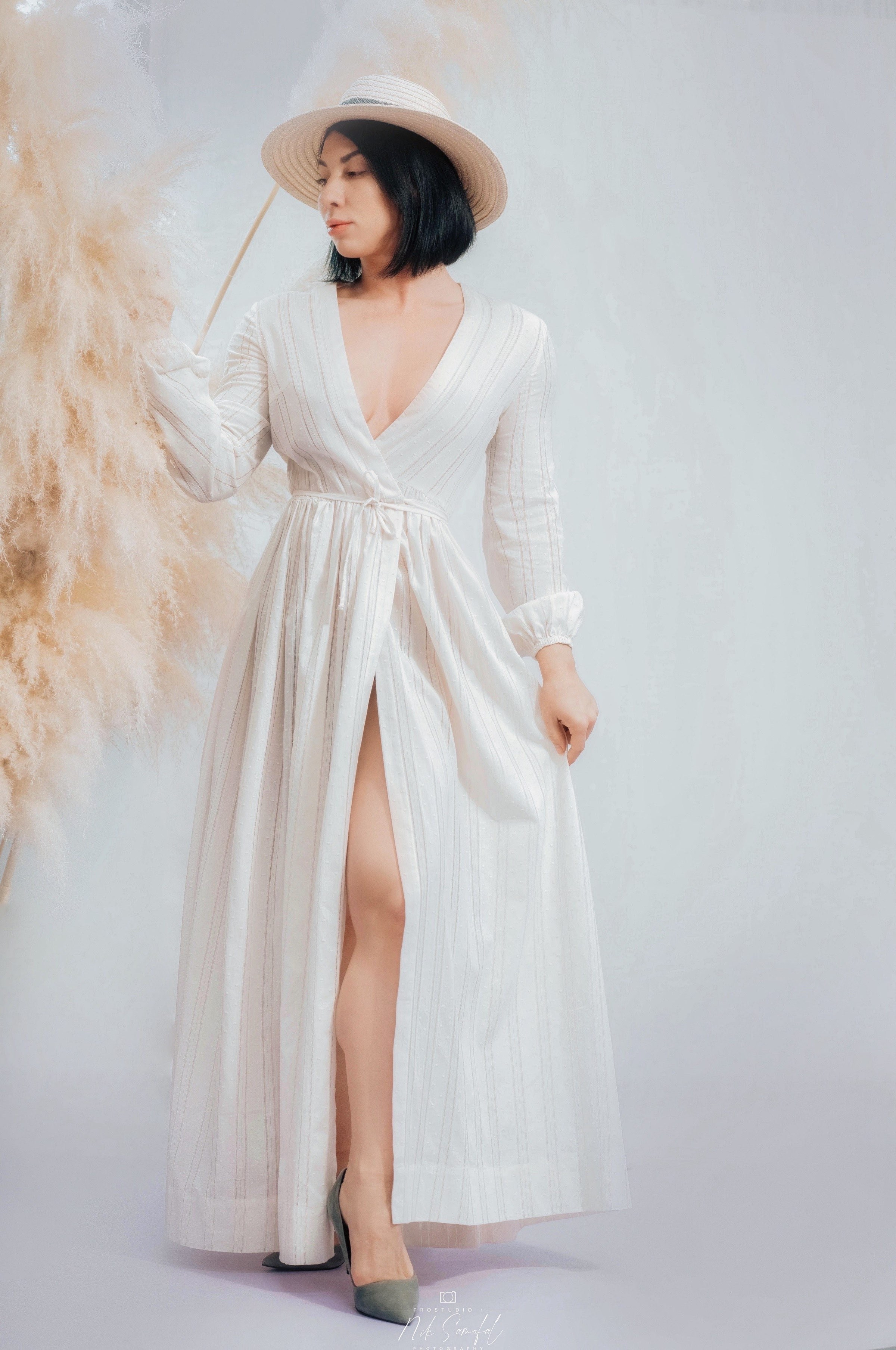 Una modelo con vestido vaporoso y sombrero de sol posa sobre el fondo blanco infinito cerca de Miami