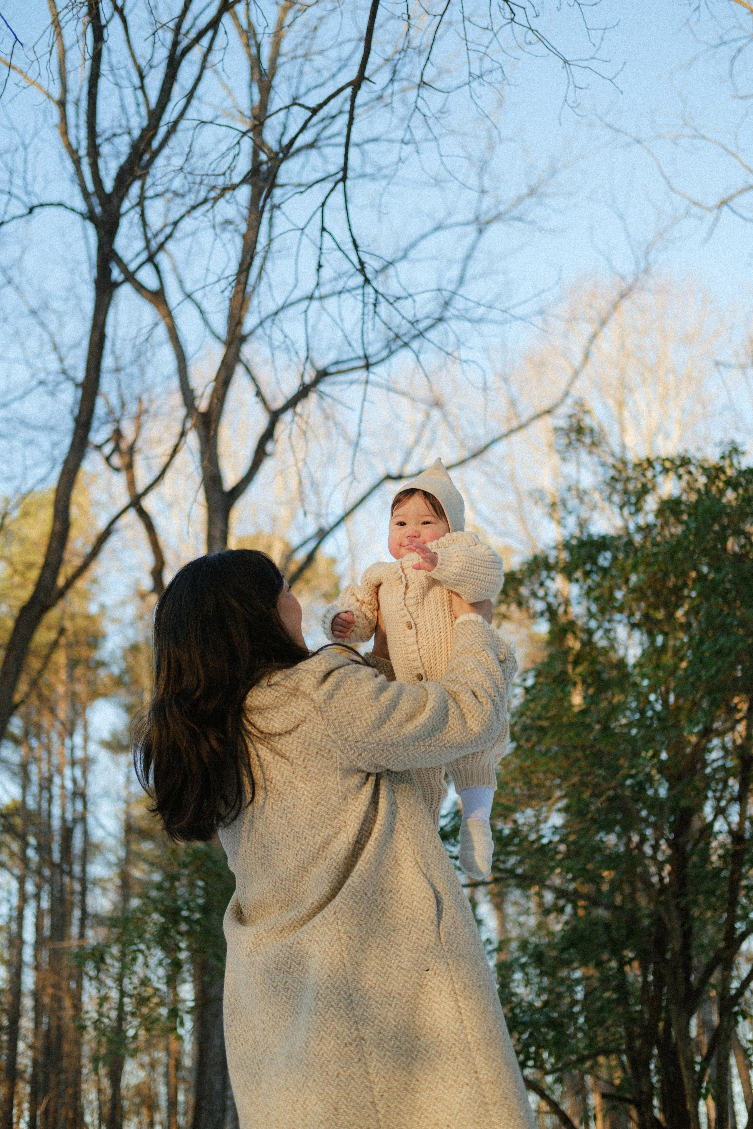 Mom is throwing her baby girl in the sky playfully, the girl is happy, its a frosty winter afternoon in Richmond, VA