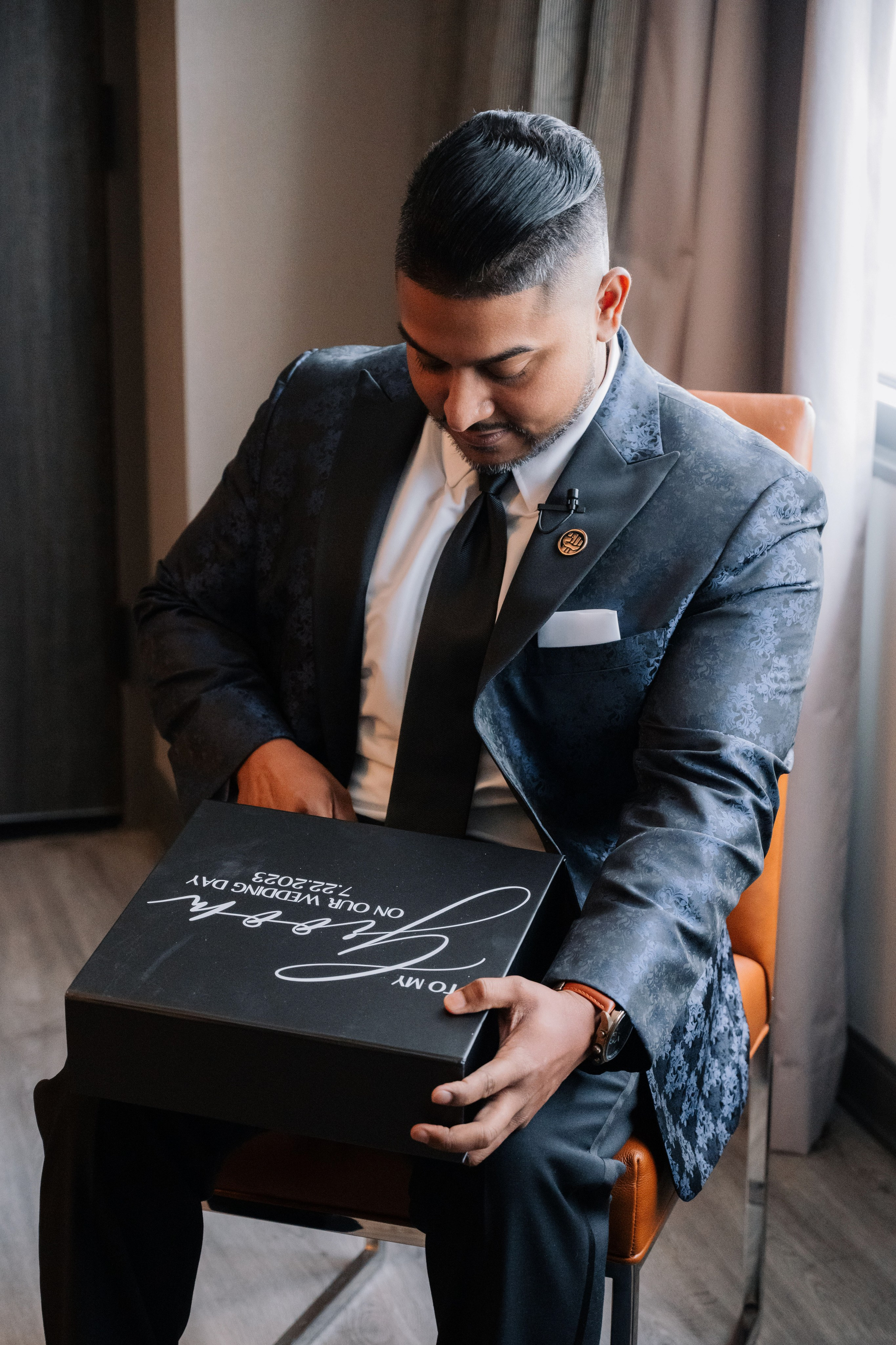 a man in a suit sitting on a chair holding a box