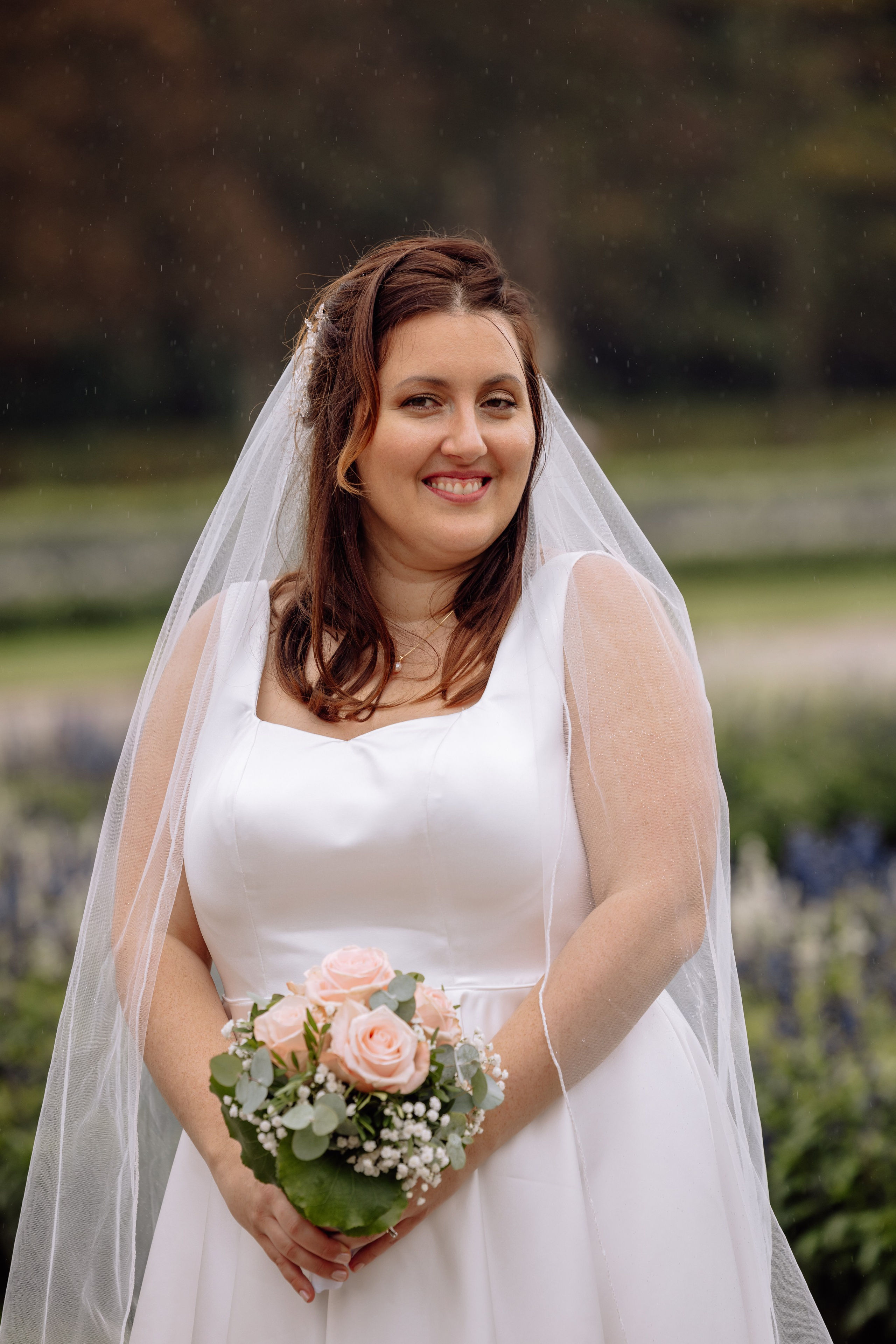 Braut lächelt und hält ihren Brautstrauß vor dem Schloss Nymphenburg