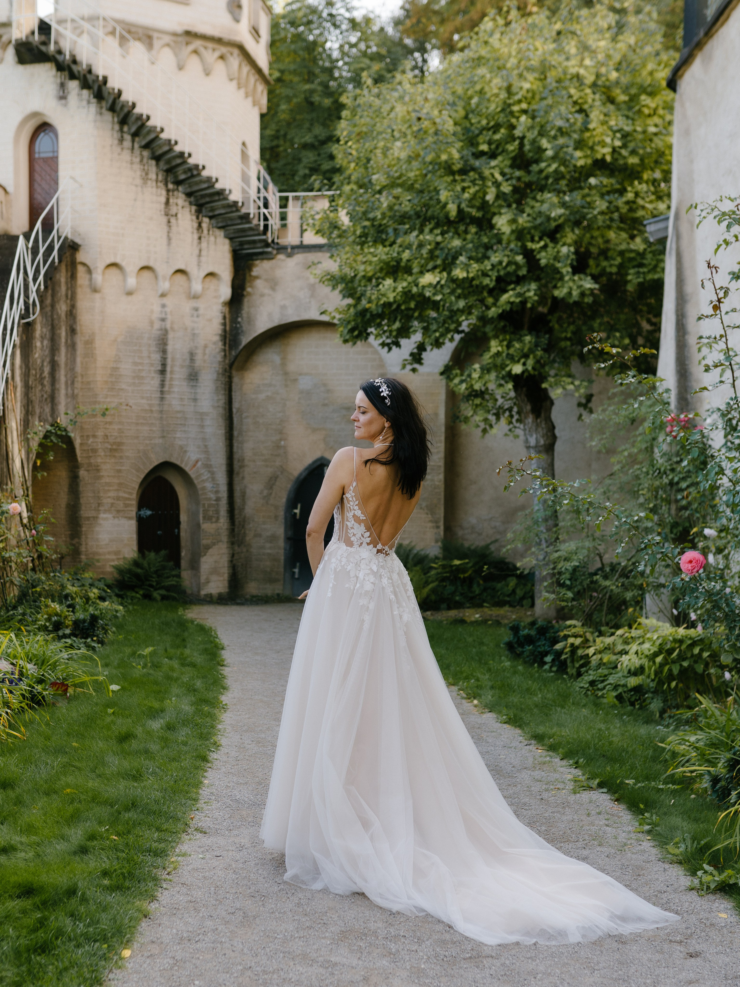 Elegante Braut in ihrem traumhaften Hochzeitskleid, das mit feinen Details und einer langen Schleppe den königlichen Charme ihres besonderen Tages unterstreicht.